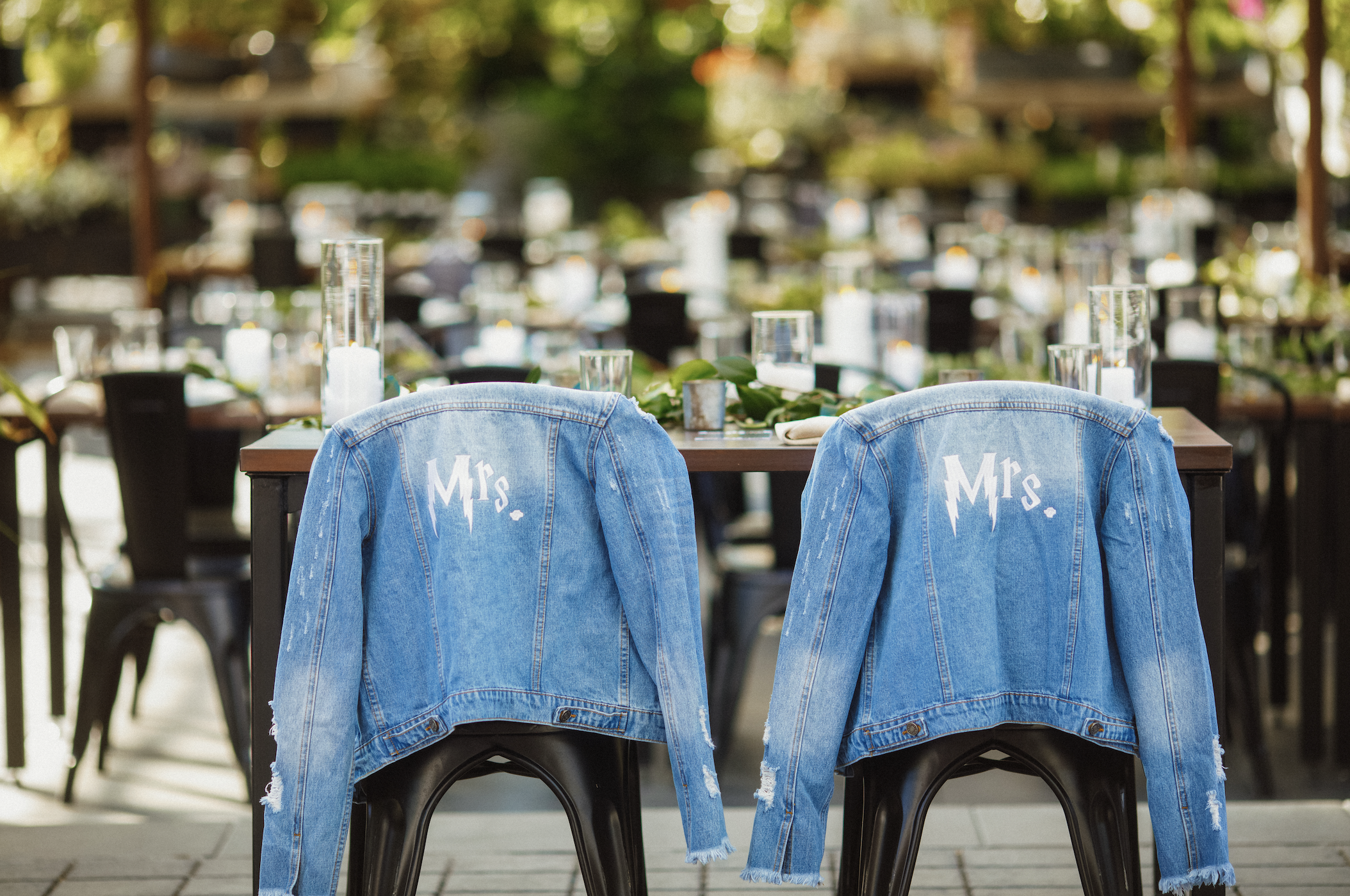 A wedding ceremony with two denim Mrs. and Mrs. jackets draped over chairs