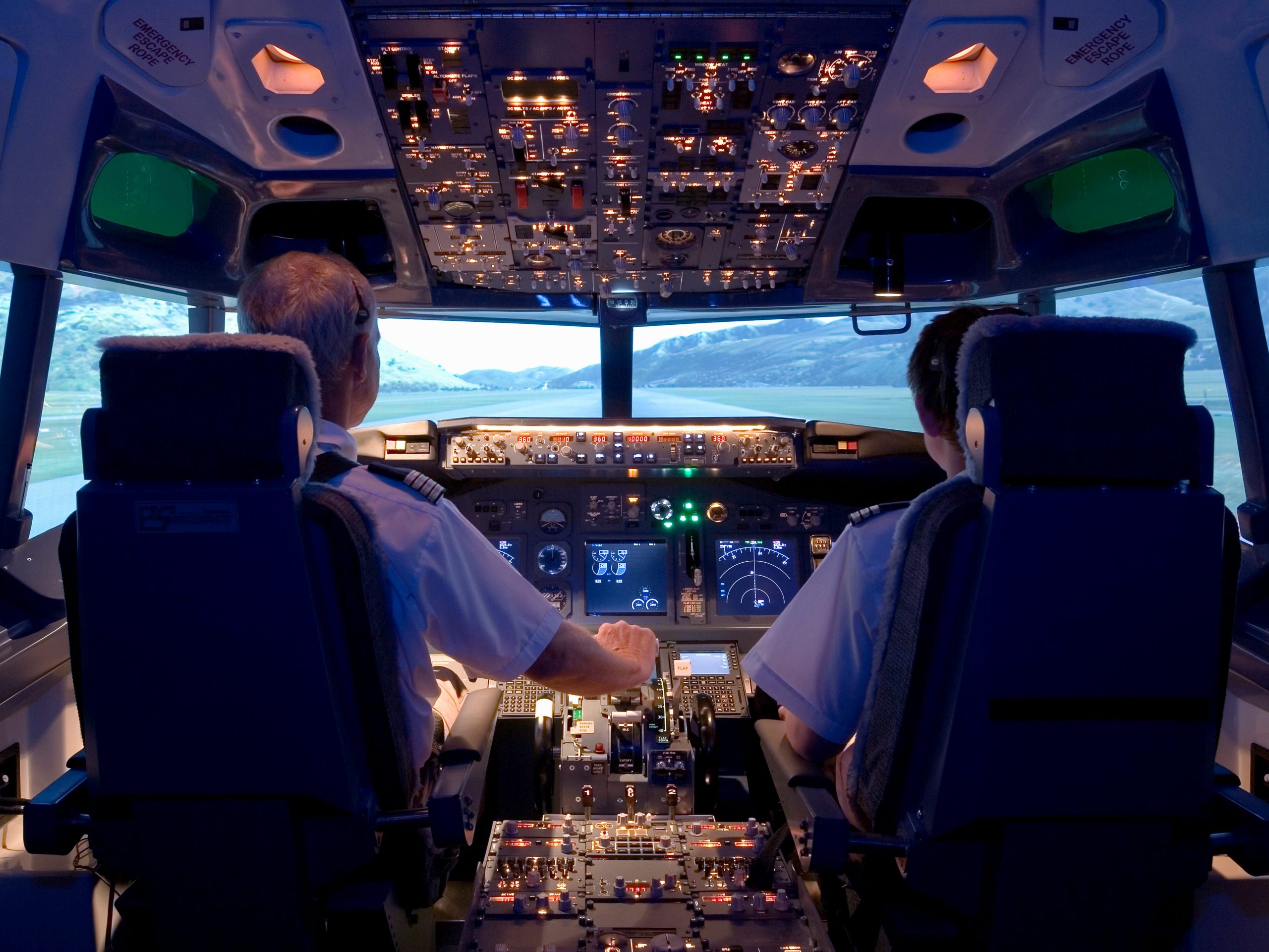 Two pilots sitting in flight simulator, rear view