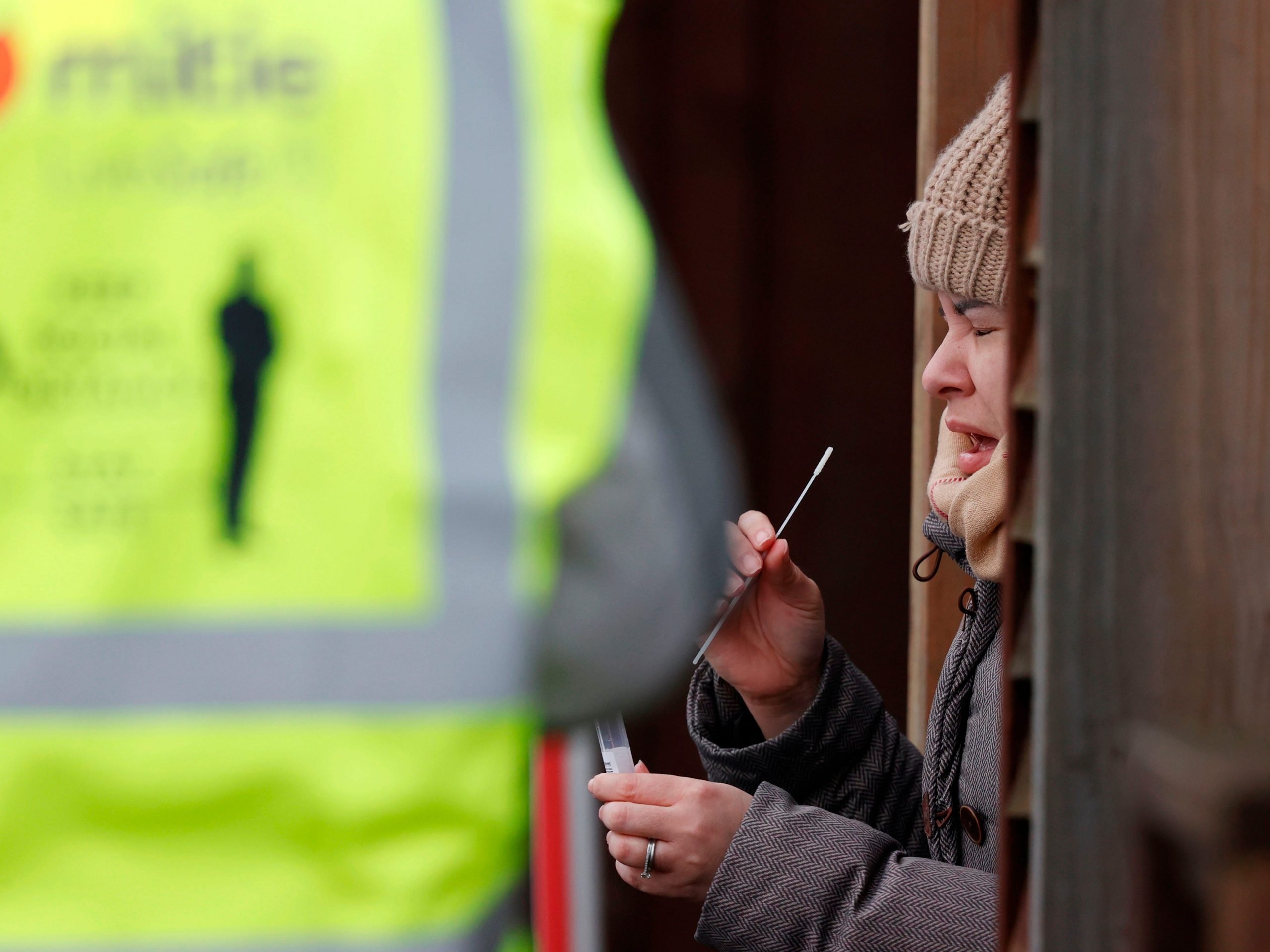 A woman swabs throat at a COVID-19 testing site in the UK.