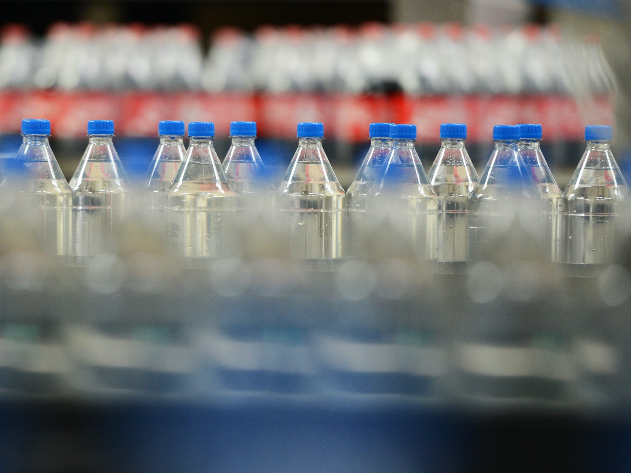 Clear bottles and Coca-Cola bottles pass on the production line in a Coca-Cola bottling plant in Germany