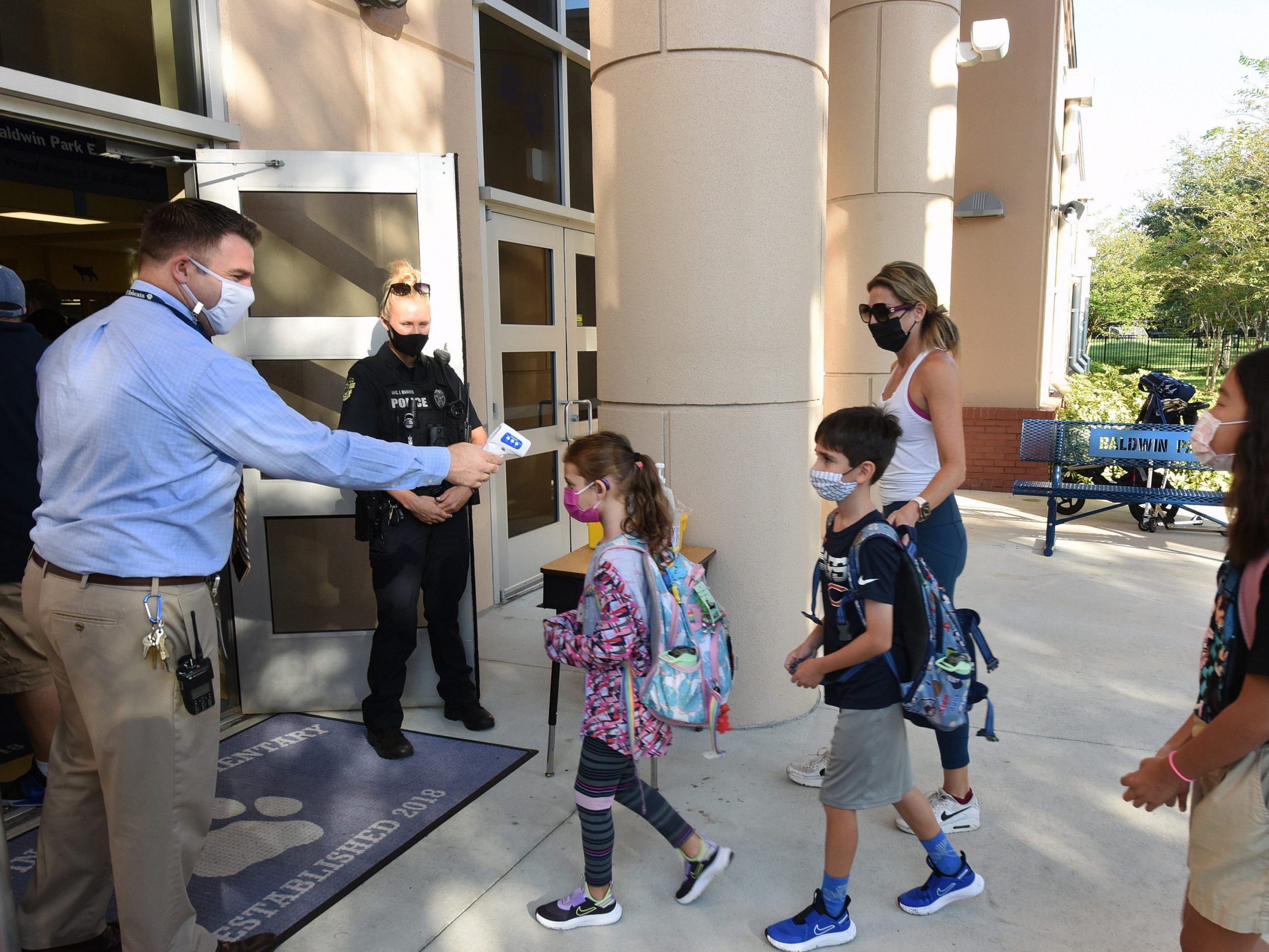 Principal Nathan Hay performs temperature checks on students as they arrive on the first day of classes for the 2021-22 school year at Baldwin Park Elementary School in Orlando, Florida, on August 10, 2021.