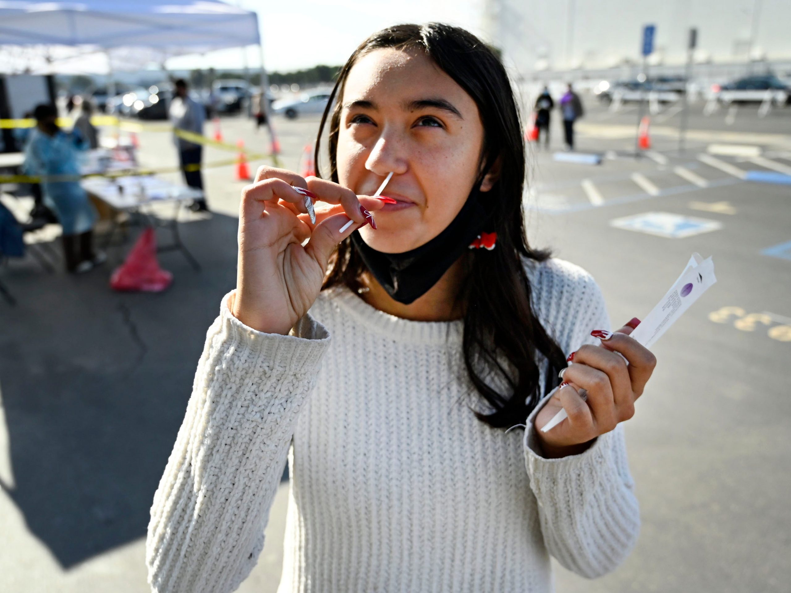 Young person takes nasal COVID-19 test in testing center.