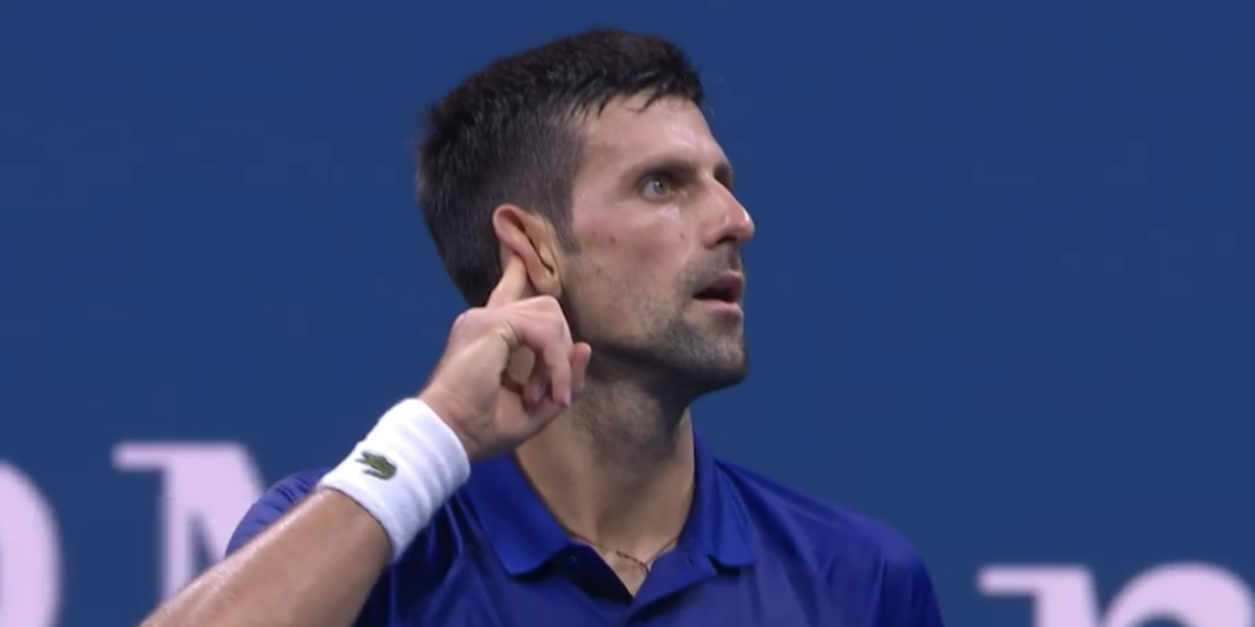 Novak Djokovic raises his finger to his ear at the US Open