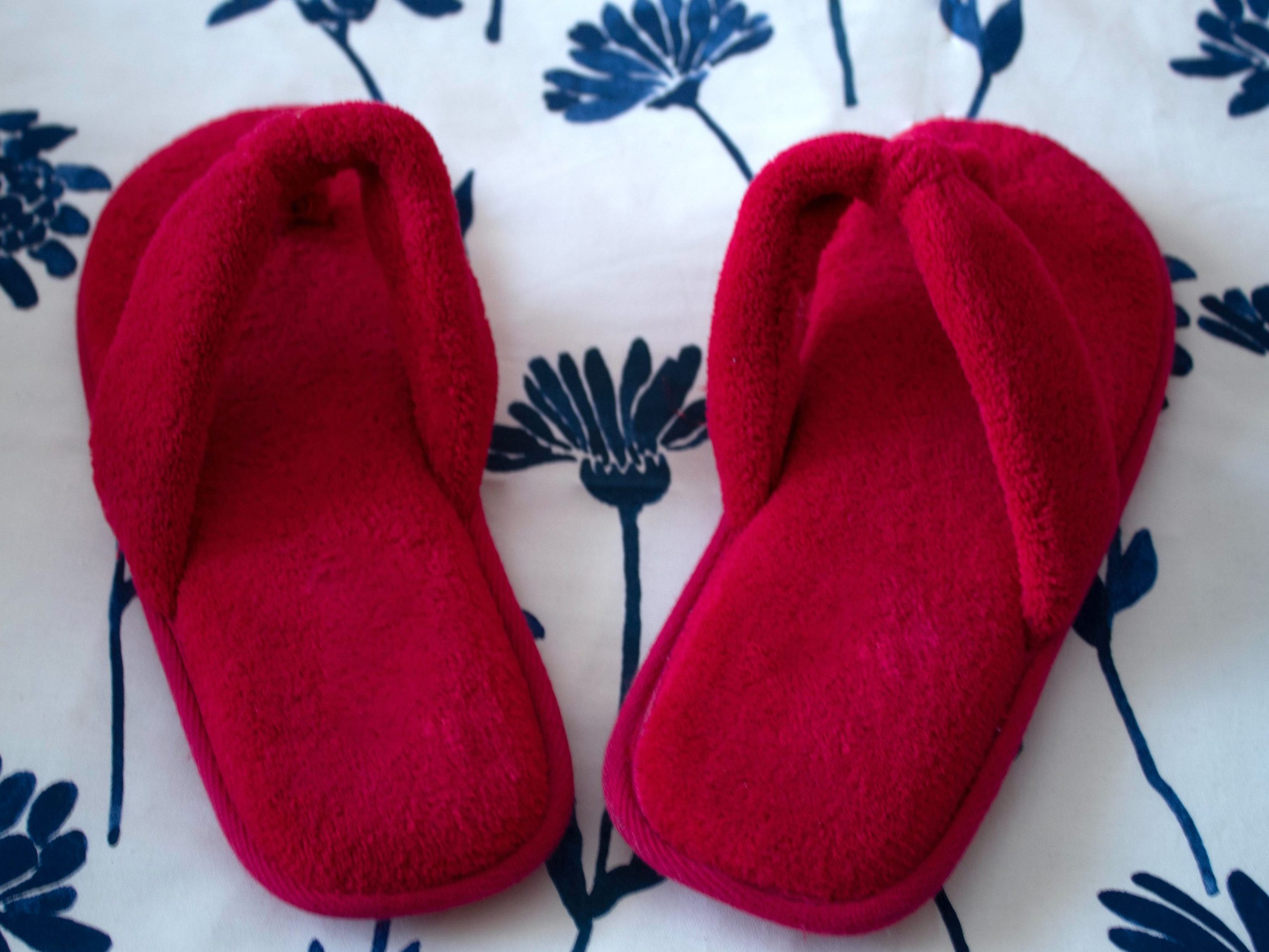 Red fuzzy slippers on blue-and-white blanket