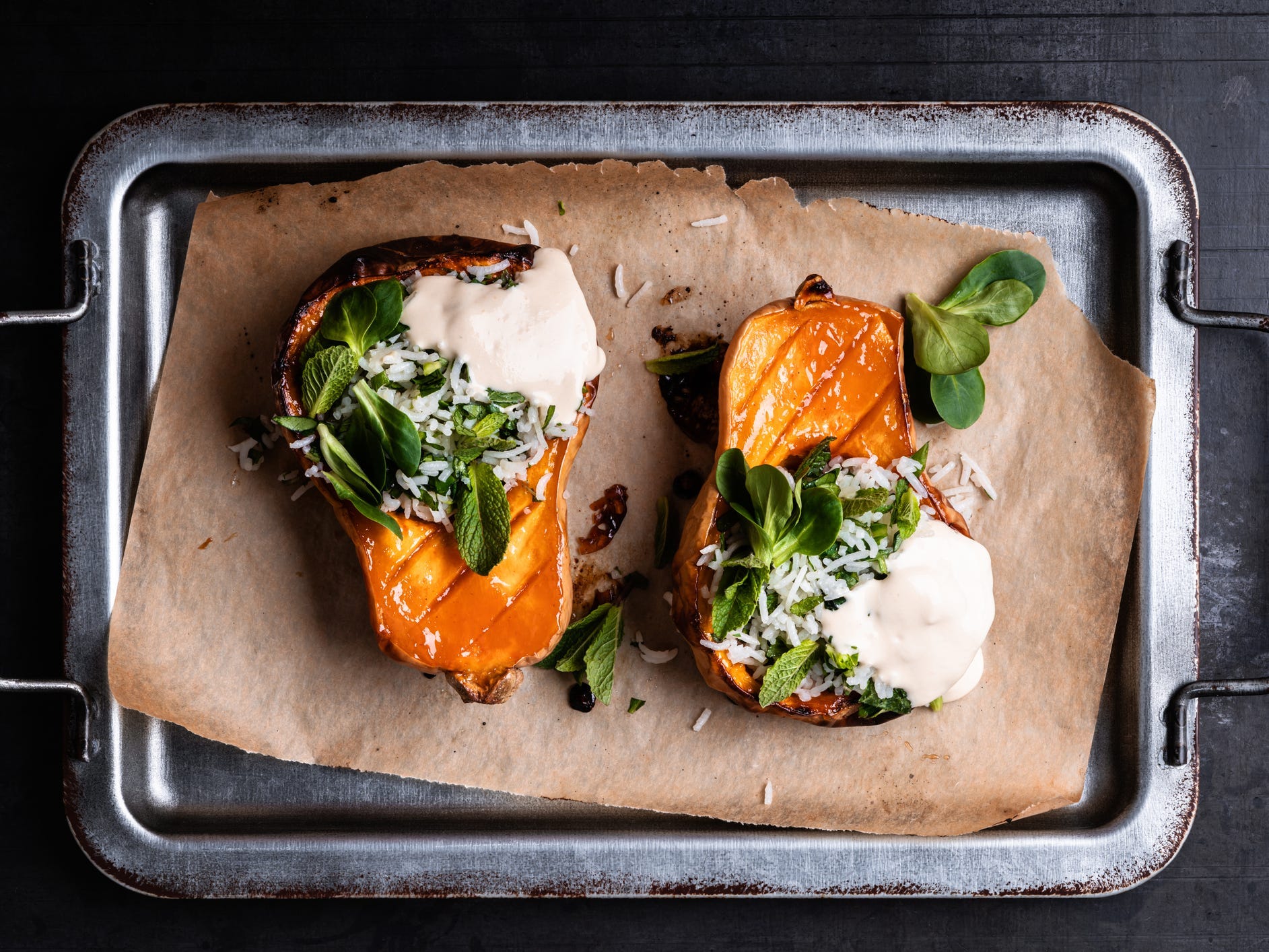 A view from above of roasted butternut squash halves stuffed with rice and herbs