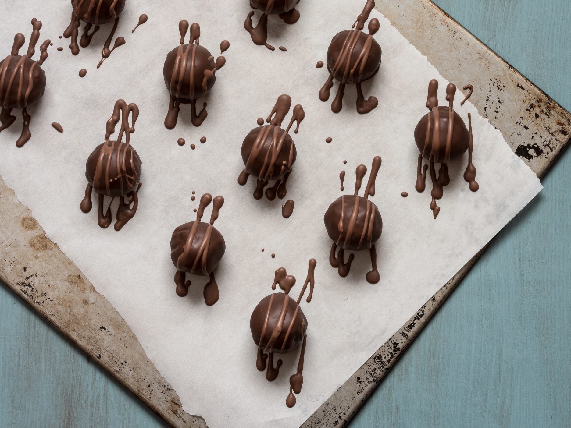 A view from above of chocolate truffles setting on a wax paper-lined baking sheet