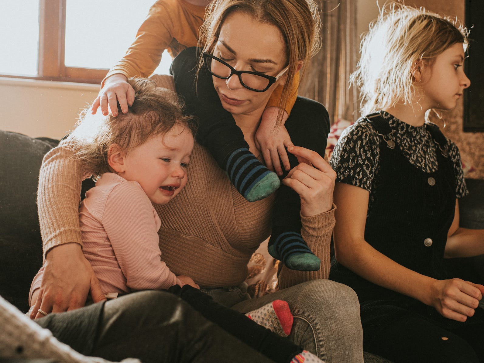 A mother with four children sits on a sofa with her kids.