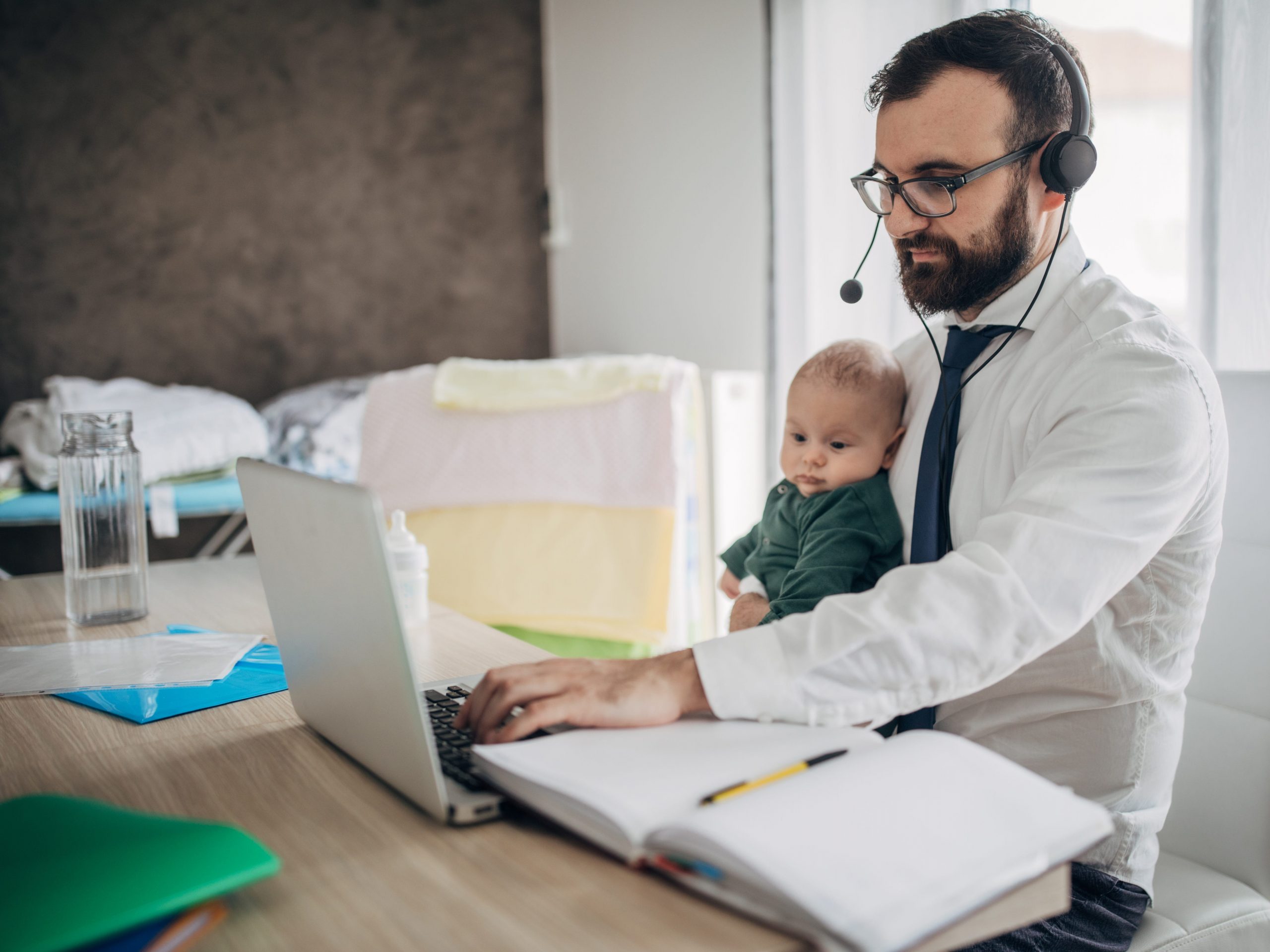 Businessman holding his baby son and working from home do to pandemic outbreak