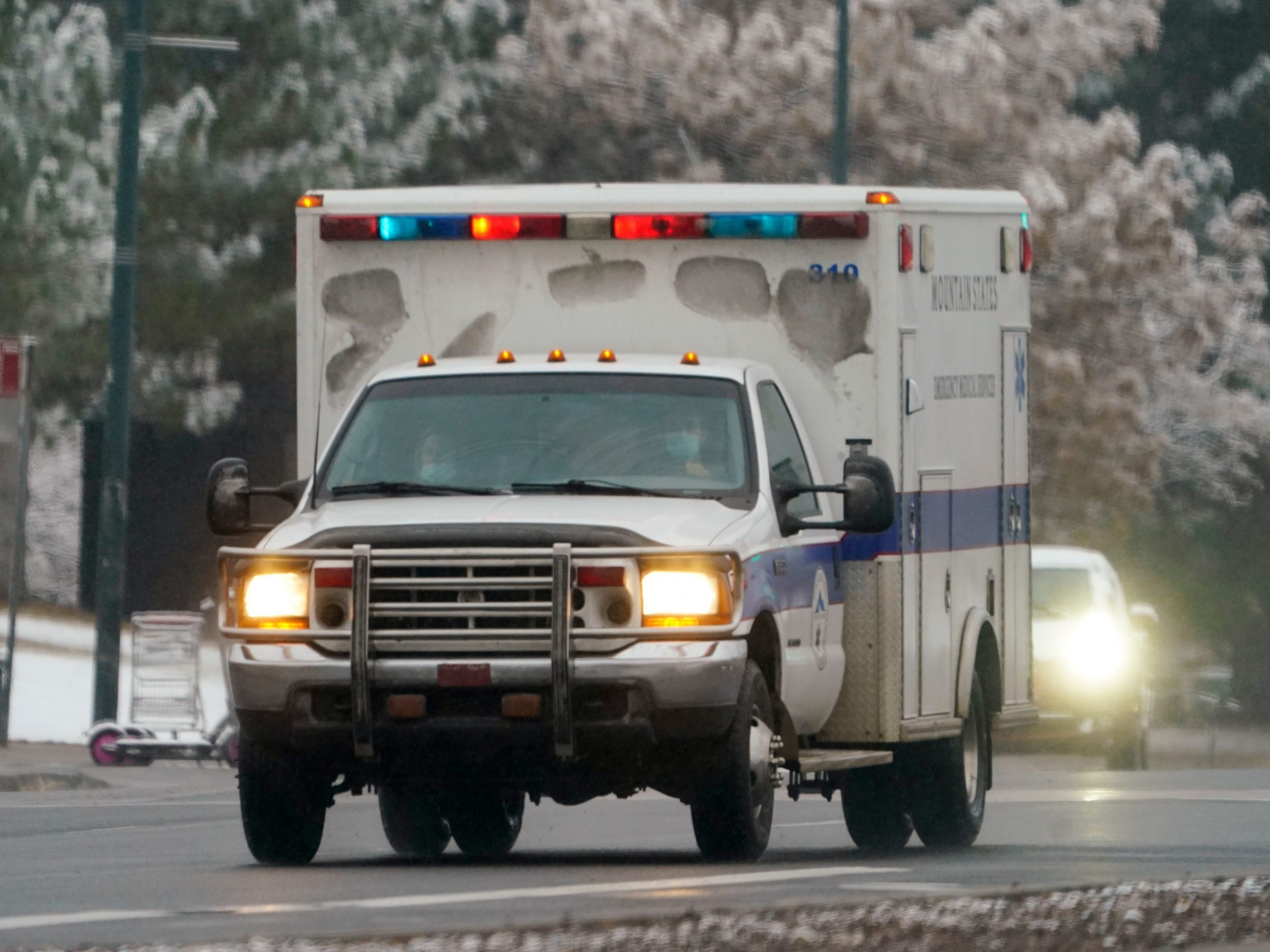 An ambulance roars along westbound West Colfax Avenue through traffic, Monday, Nov. 9, 2020, in downtown Denver.