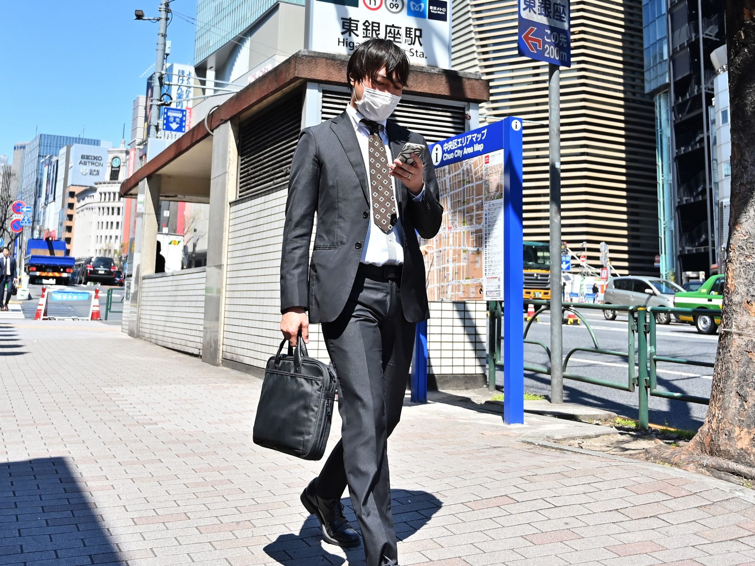 A businessman checks his phone as he walks along the pavement in Tokyo's Ginza district.
