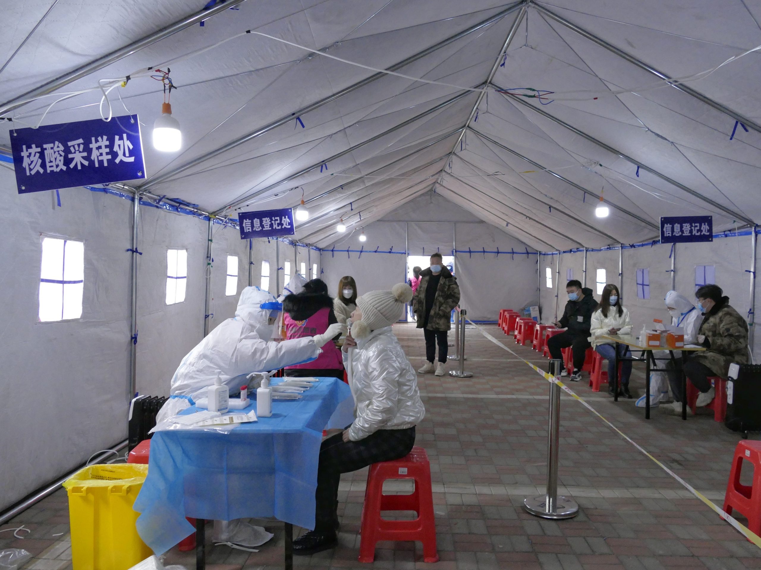 A medical worker collects a throat swab from a resident at a nucleic acid site in Tianjin, China.