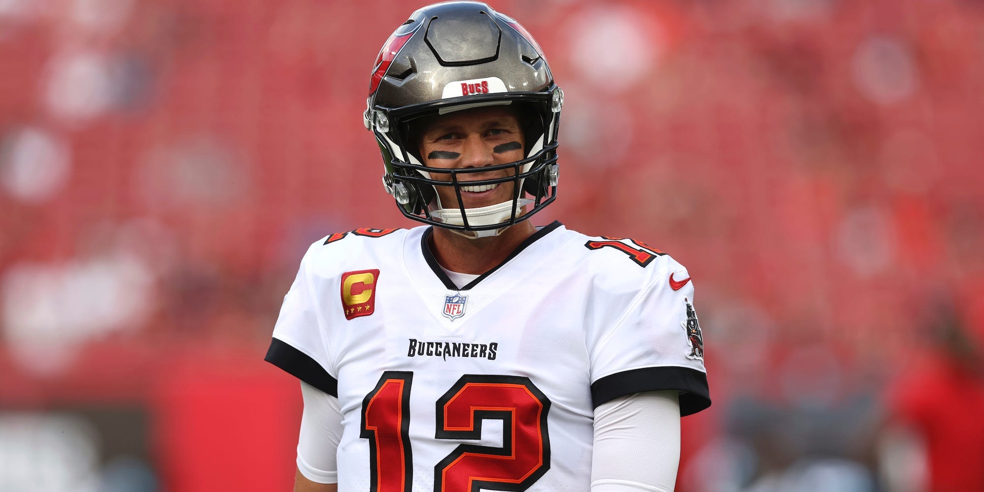 Tom Brady smiles on the field during a game in 2022.