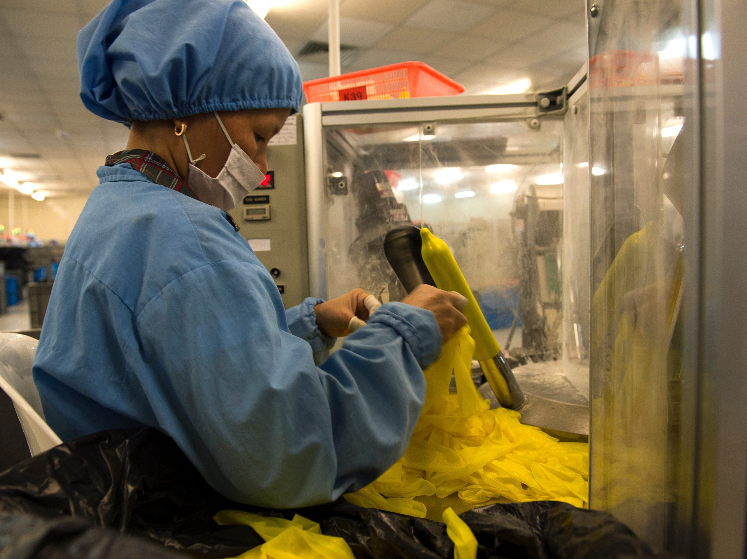 A worker in protective wear testing condoms quality at a production line at Karex industries in Malaysia's southern seaside town of Pontian.