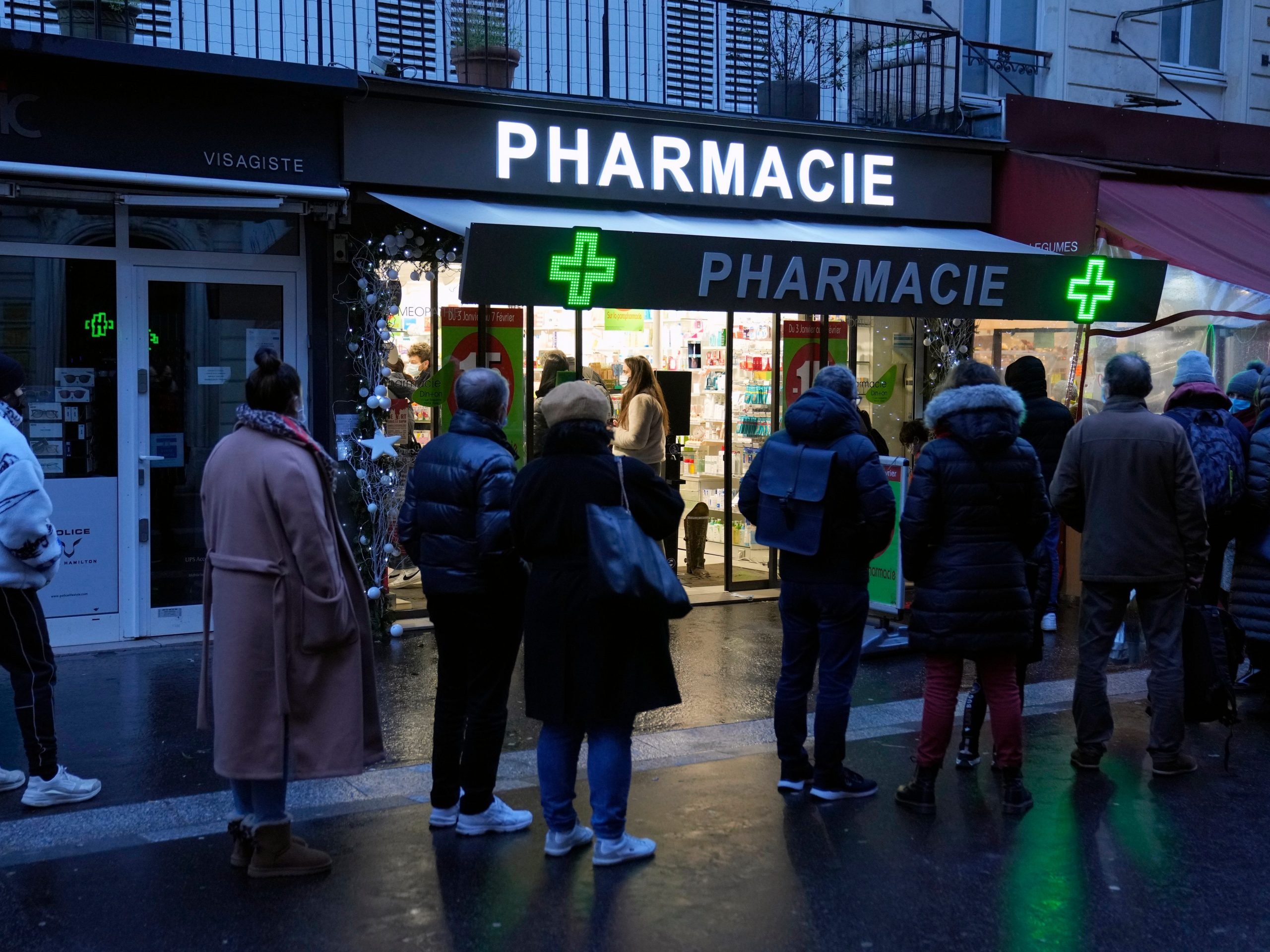 People wait in front of a pharmacy open on Sunday to get a COVID-19 test, in Paris, France, Sunday, Jan. 9, 2022.