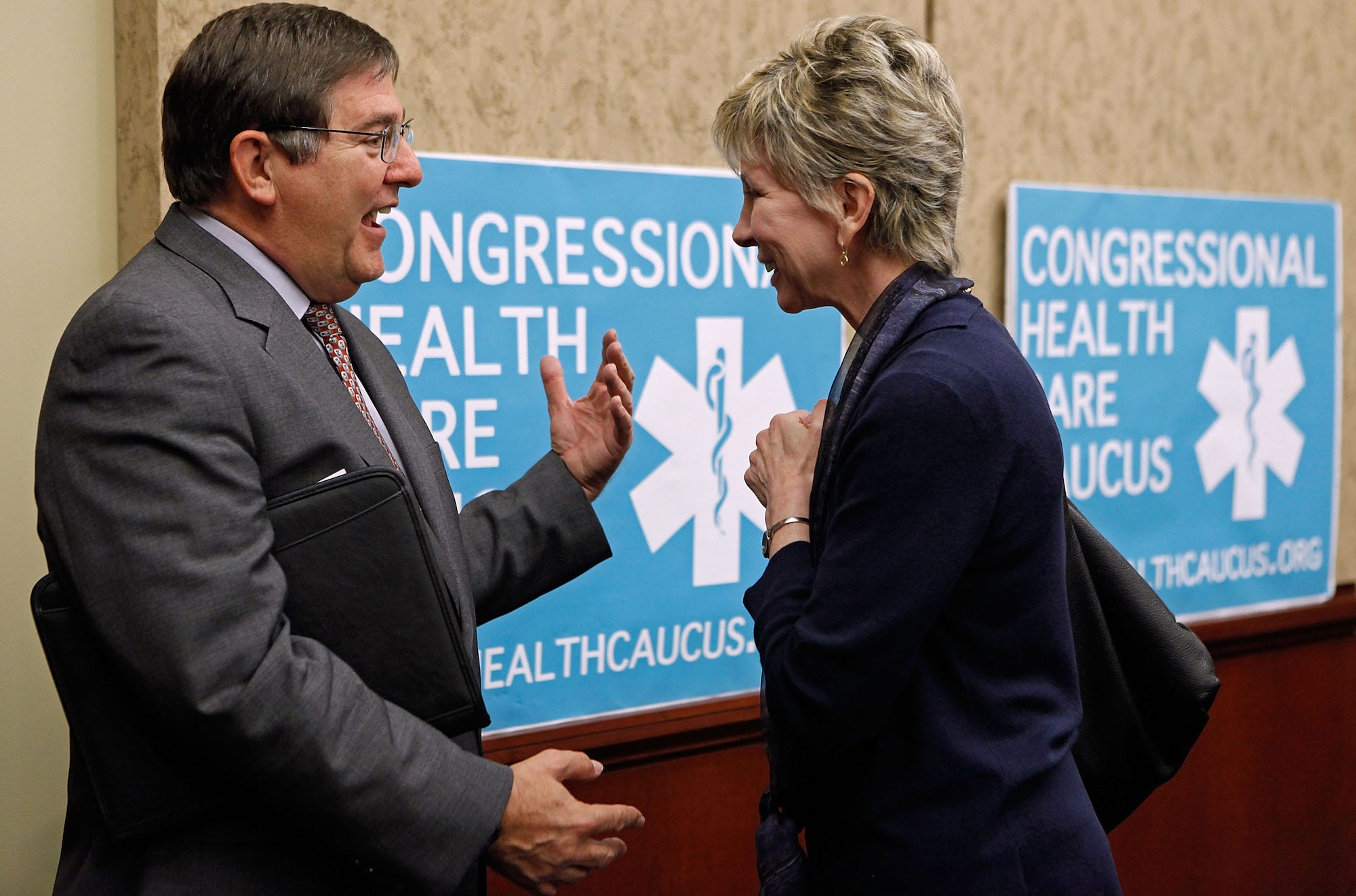 Rep. Michael Burgess, a Republican of Texas, smiles and gestures while greeting America's Health Insurance Plans President and CEO Karen Ignagni during a policy meeting on Capitol Hill.