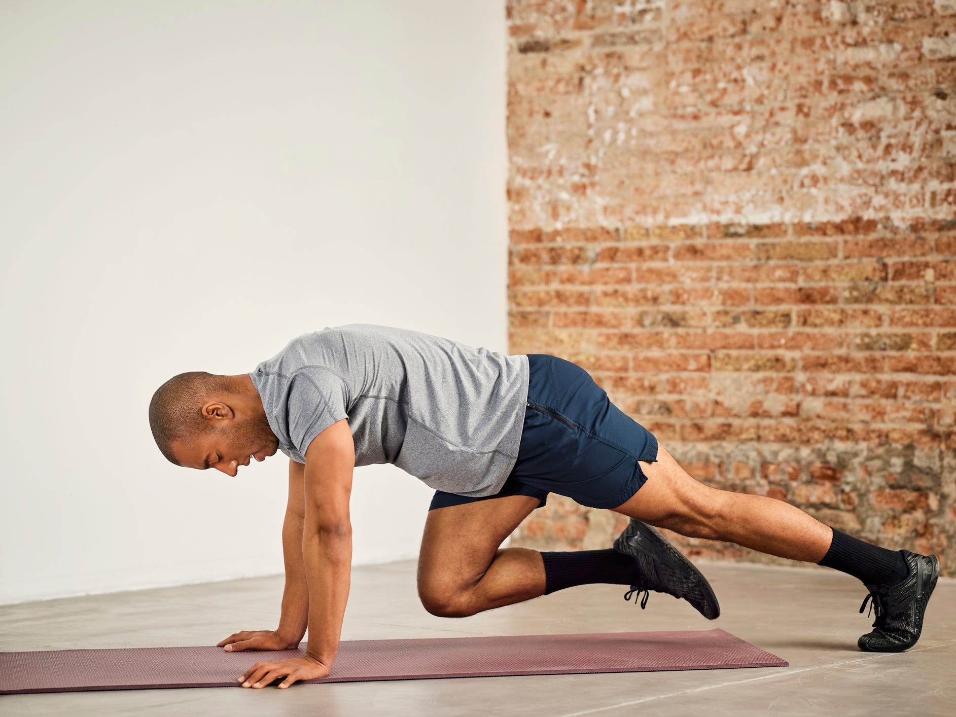 a man performing mountain climber exercises with bodyweight on a yoga mat in a studio