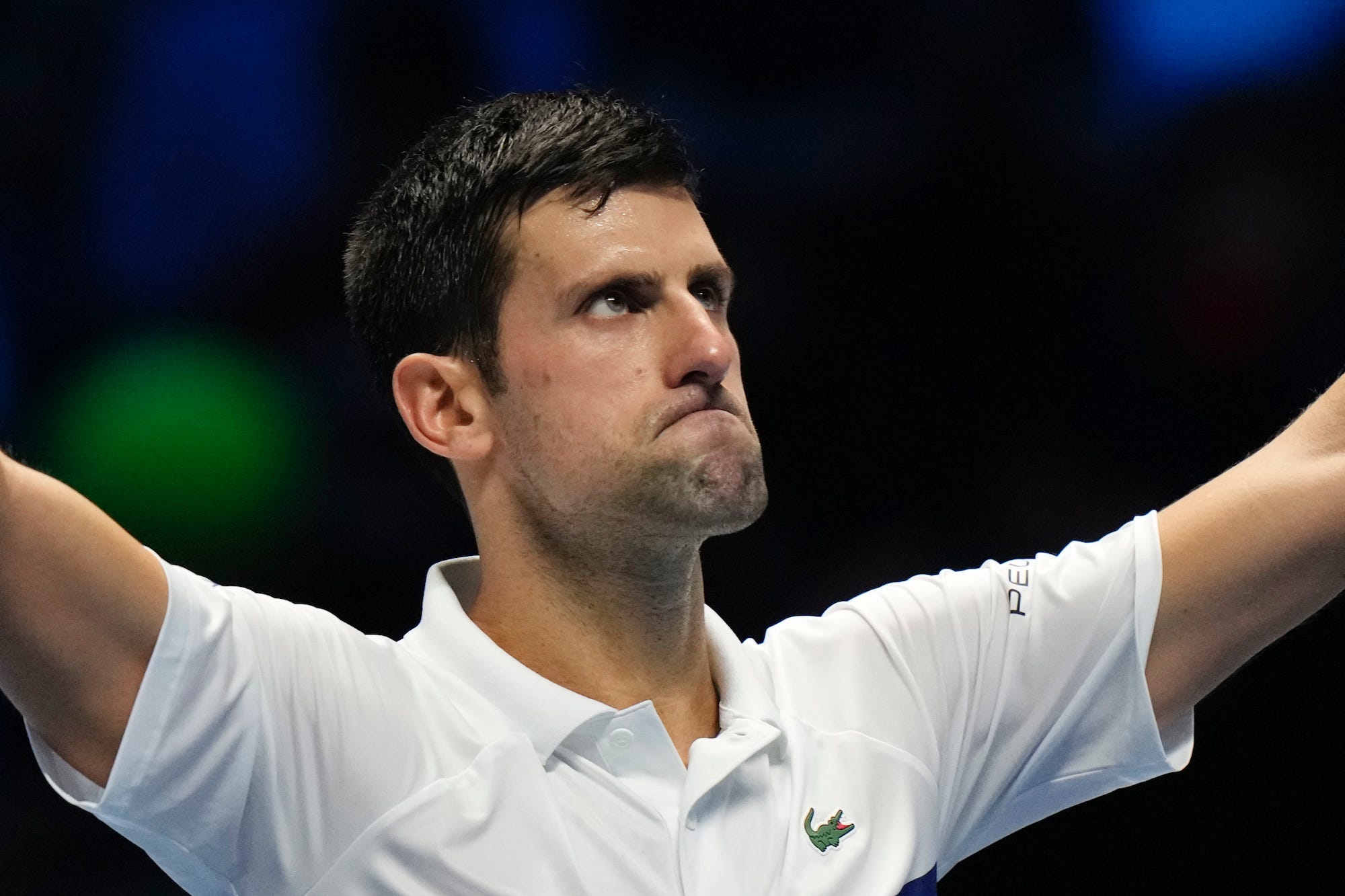 Novak Djokovic raises his arms and looks at the crowd after a match in 2021.