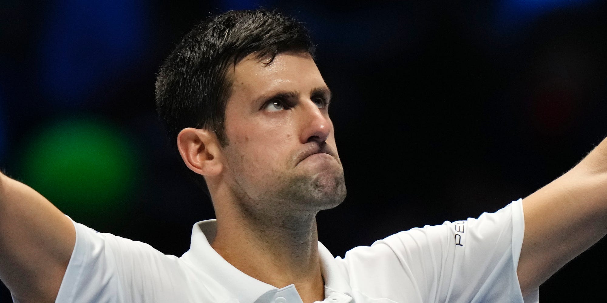 Novak Djokovic raises his arms and looks at the crowd after a match in 2021.