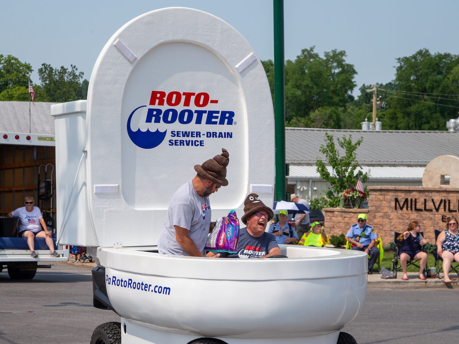 two men riding in toilet-shaped parade float