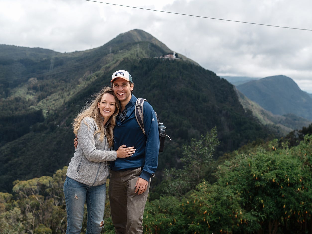 a couple pose on a green mountain