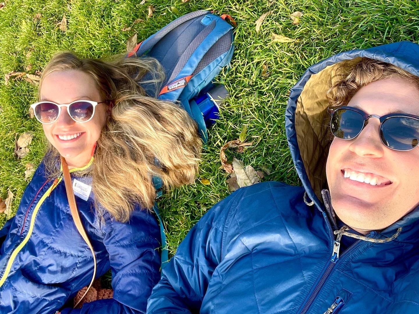 a couple lays in the grass in blue jackets