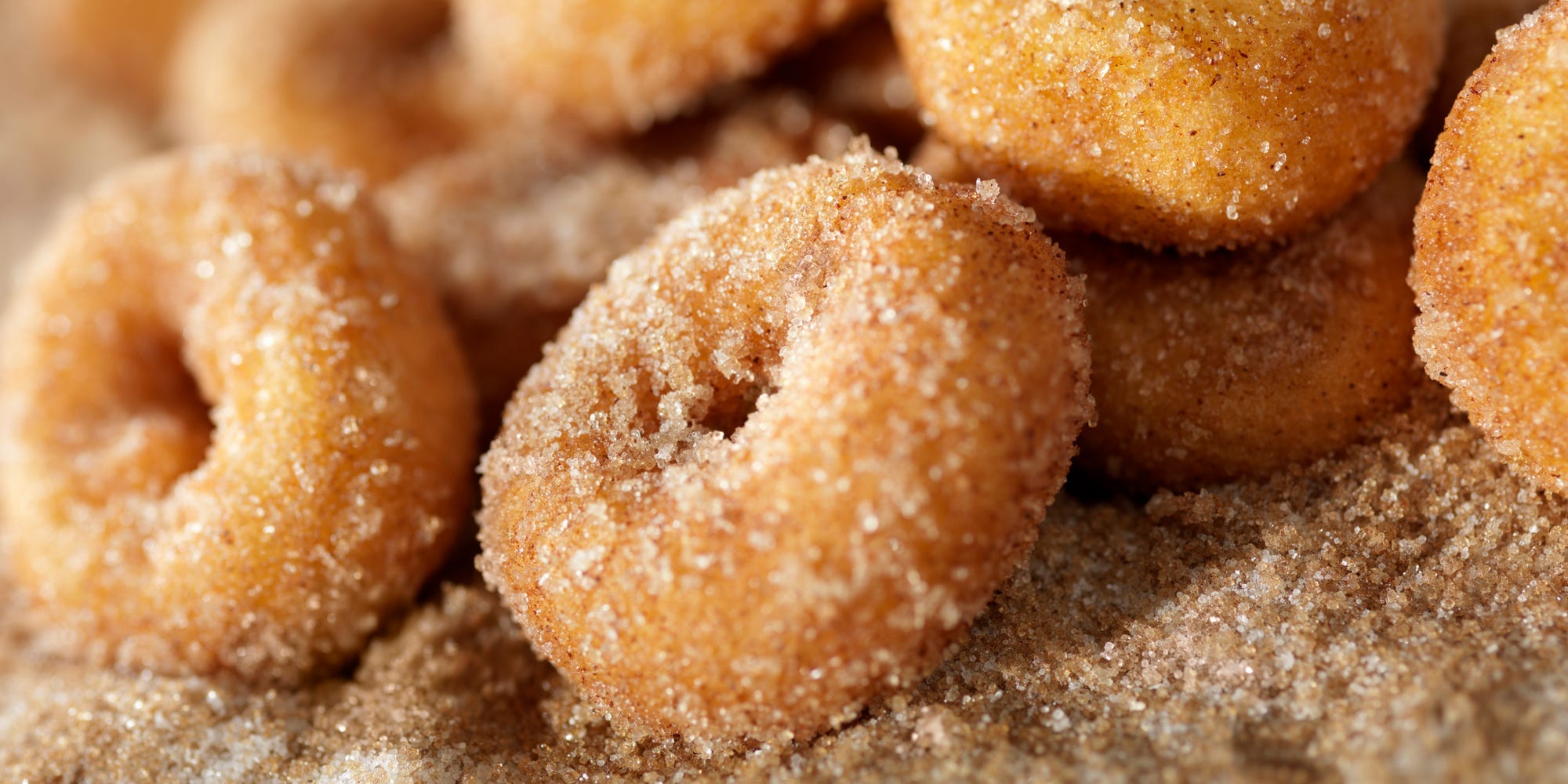 A closeup of a pile of mini donuts covered in cinnamon sugar