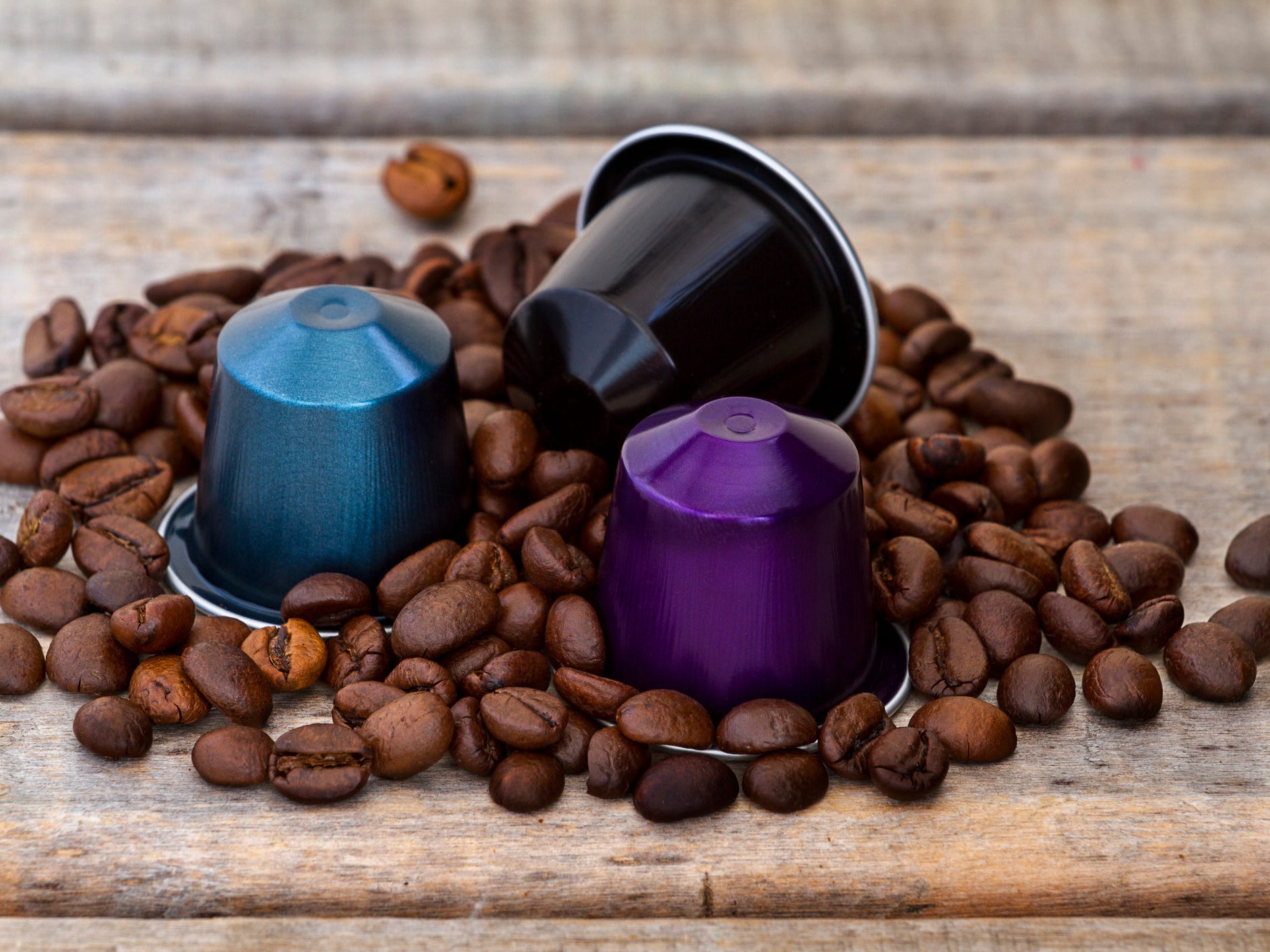 Three coffee pods sitting in a pile of whole coffee beans