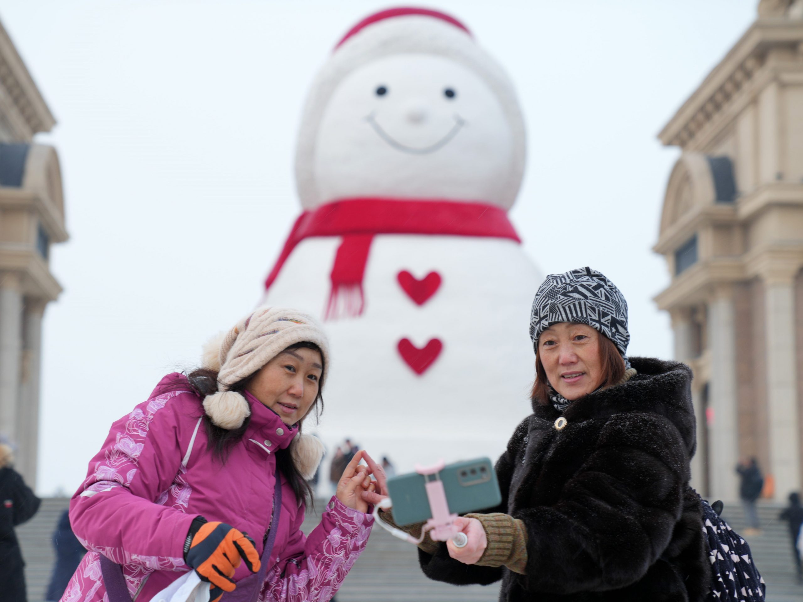 Tourists pose for photos with a huge snowman on the riverbank of Songhua River in Harbin, capital of northeast China's Heilongjiang Province, Jan. 9, 2022.
