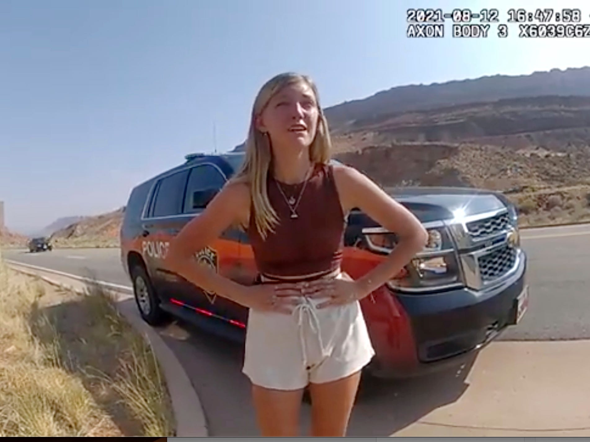 gabby petito with her hands on her hips in front of an SUV in the desert