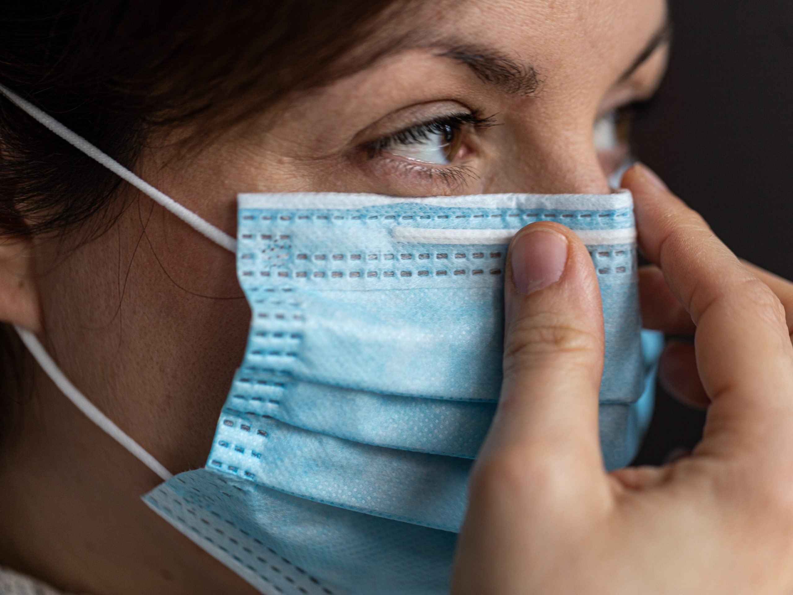 Close up of women with brown eyes wearing surgical mask.