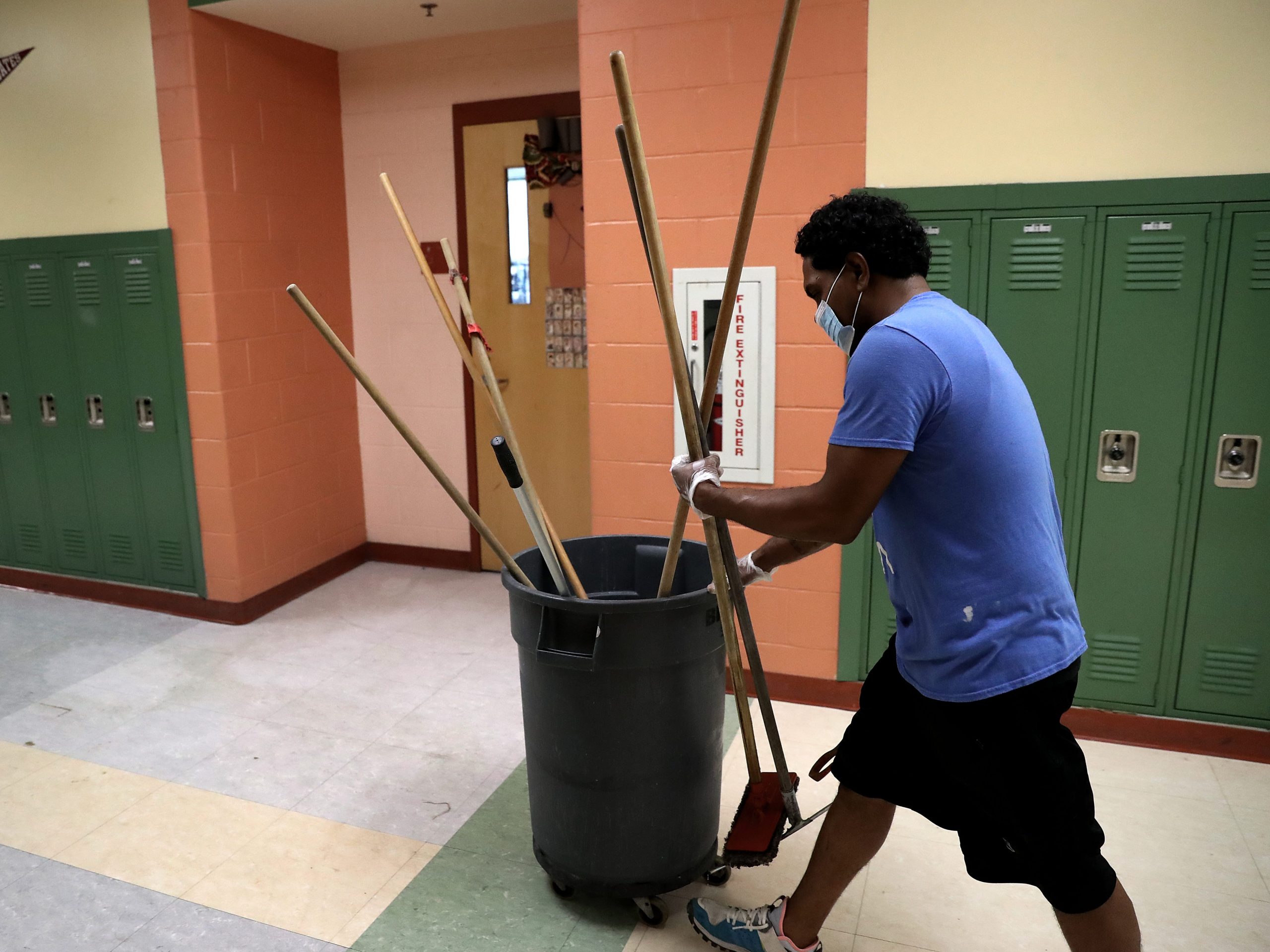 A custodian travels with supplies down the hall at the Mildred Avenue K-8 School building in Boston's Mattapan and for the reopening of school on July 9, 2020.