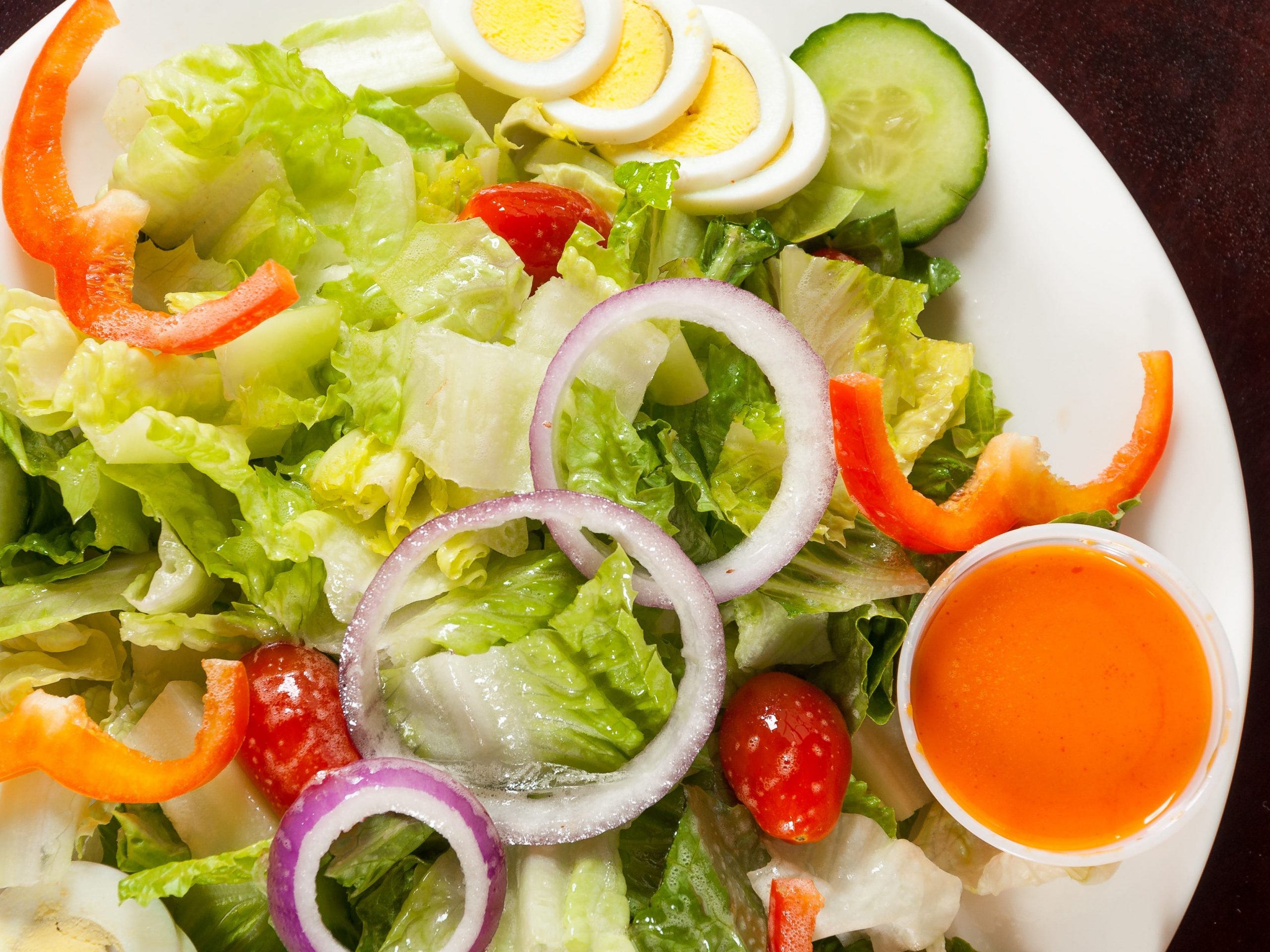 Salad with lettuce, cucumber, eggs, peppers, tomatoes, and French dressing