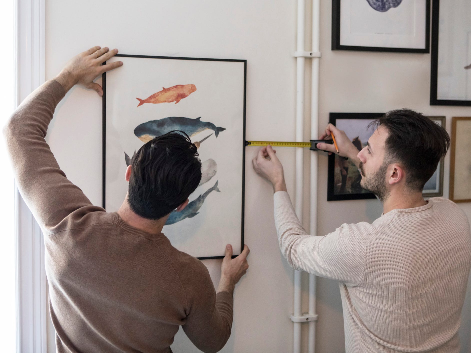 A couple measuring the location of a picture they're hanging on the wall