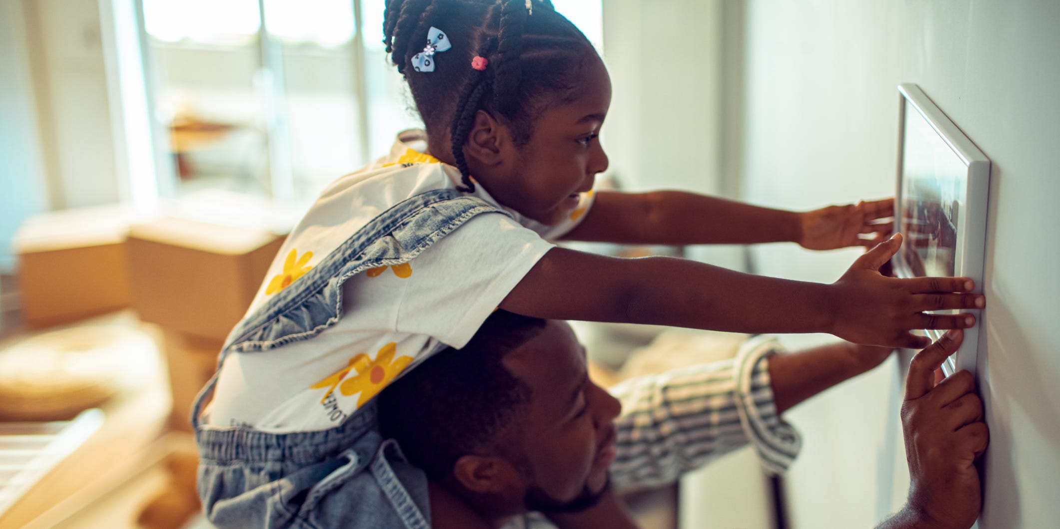 A father and daughter hanging a picture on the wall