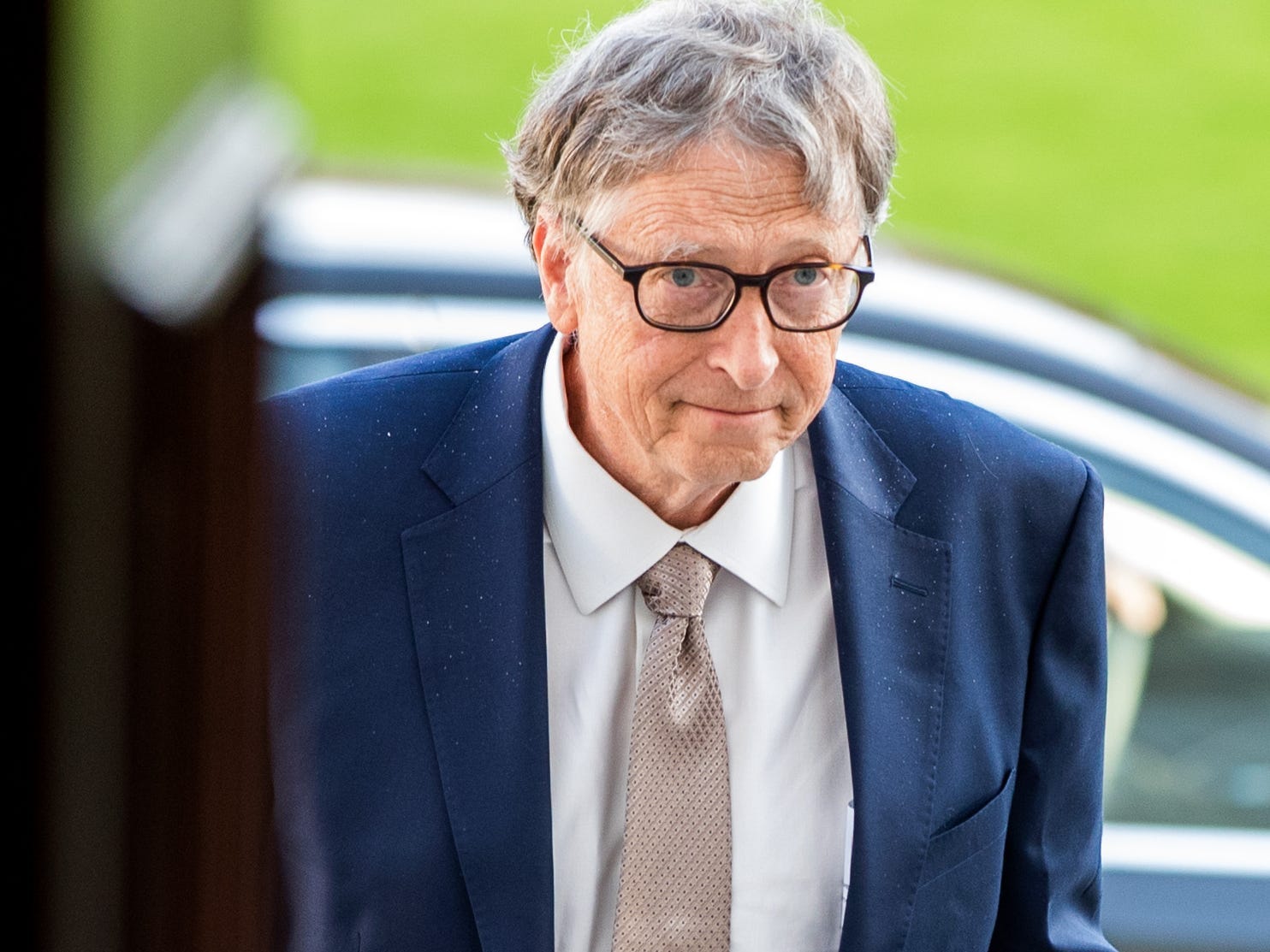 Microsoft's Bill Gates walking up stairs in front of a green field