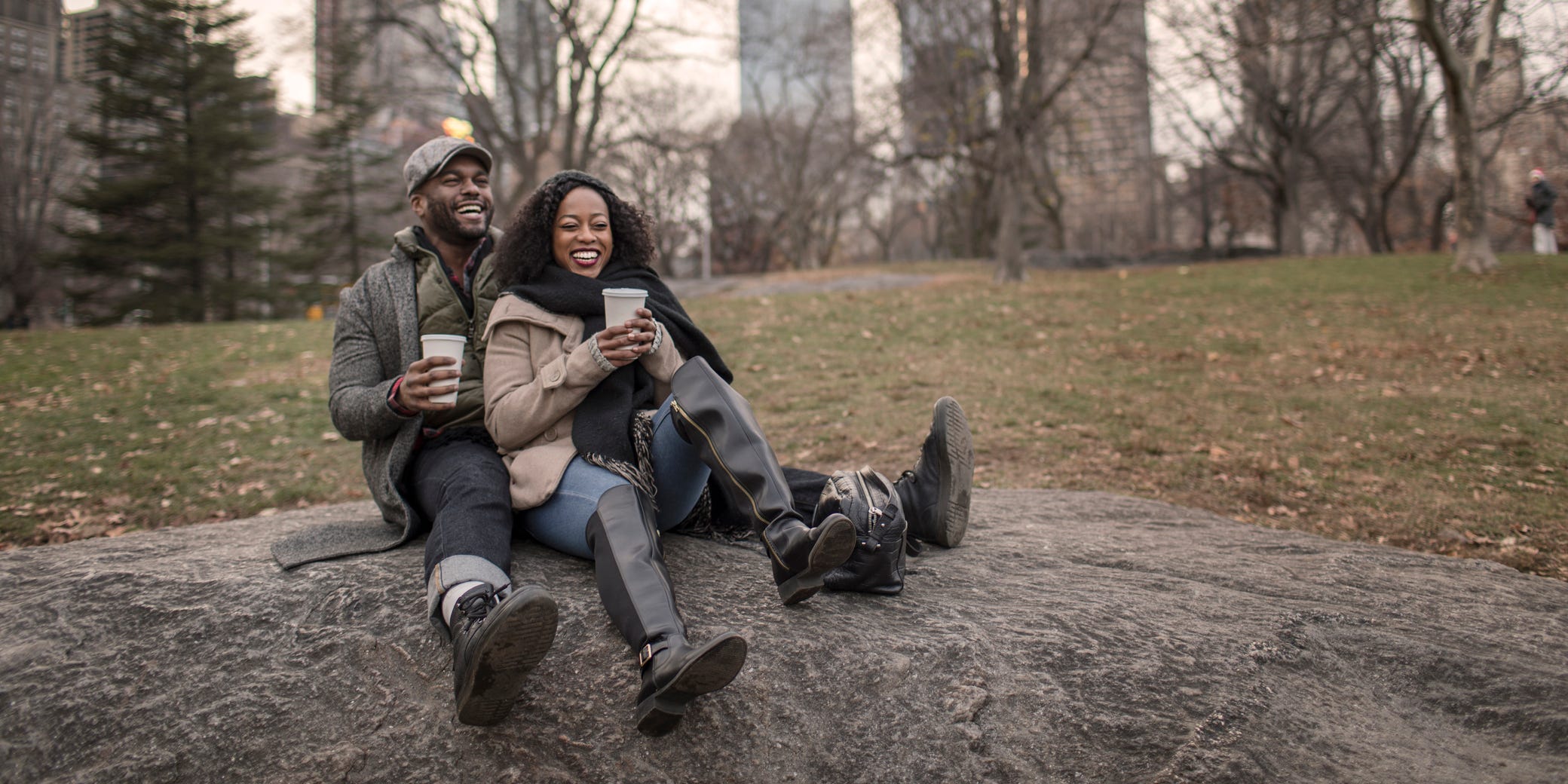 A couple sits sipping coffee in a park.