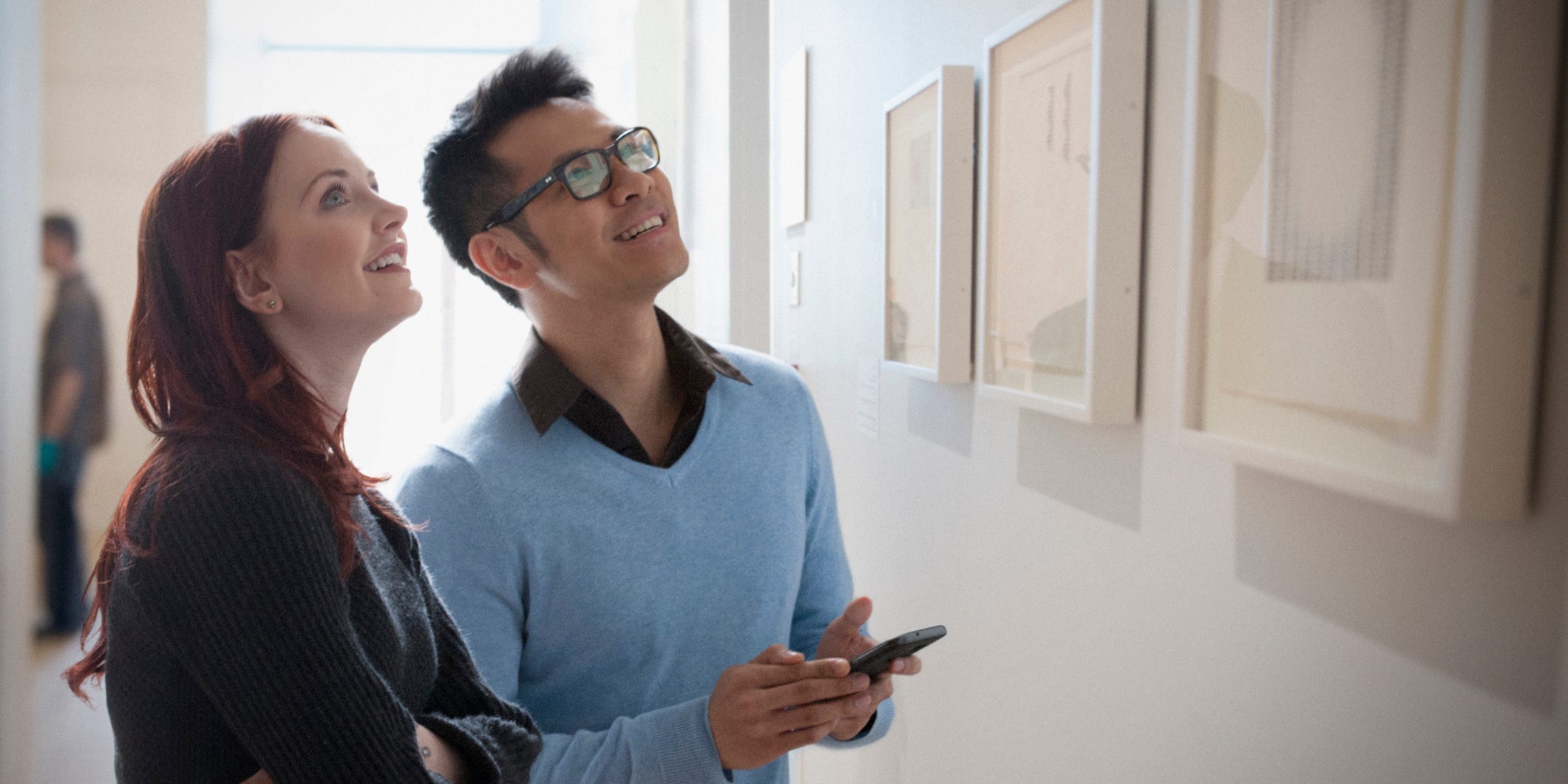 A couple stands in an art museum marveling at some photographs.