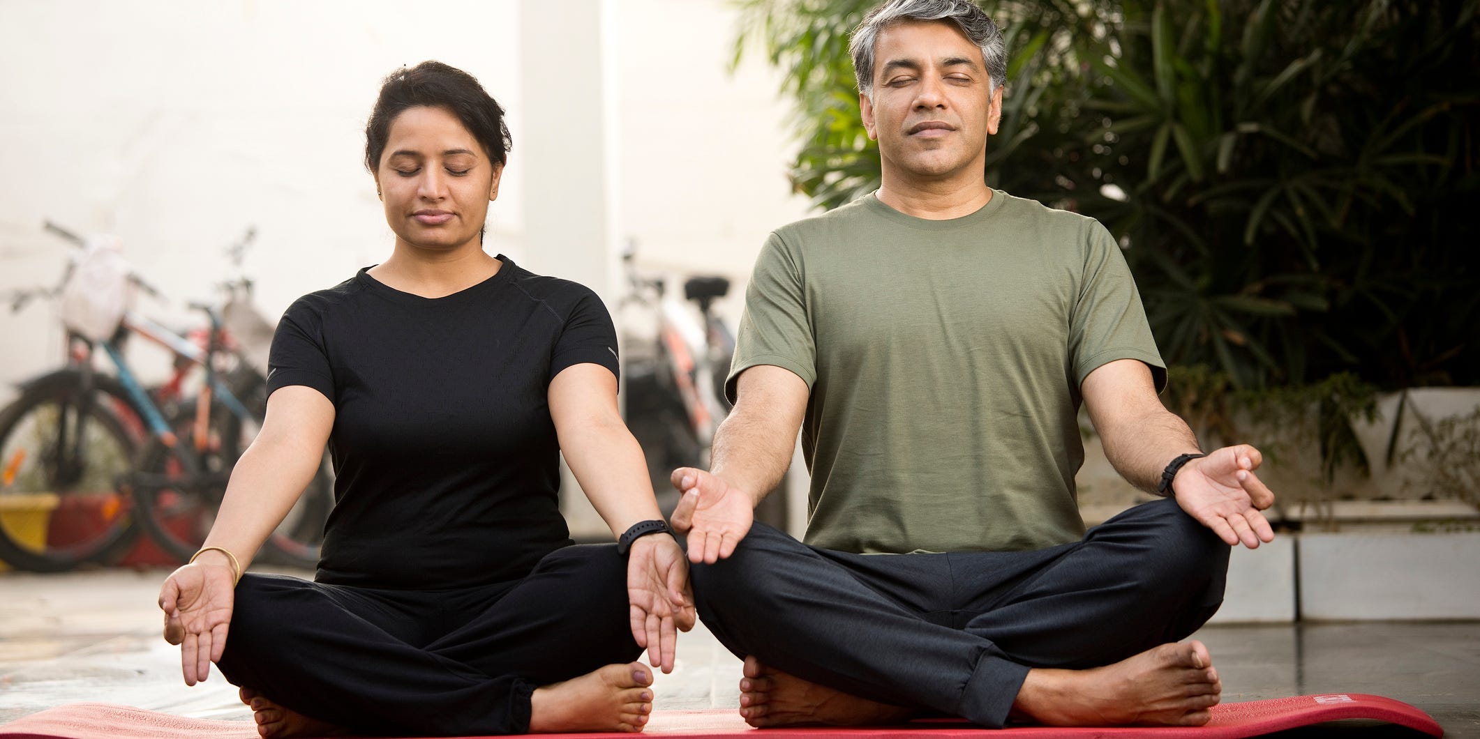 A couple sits in a meditative pose breathing together.