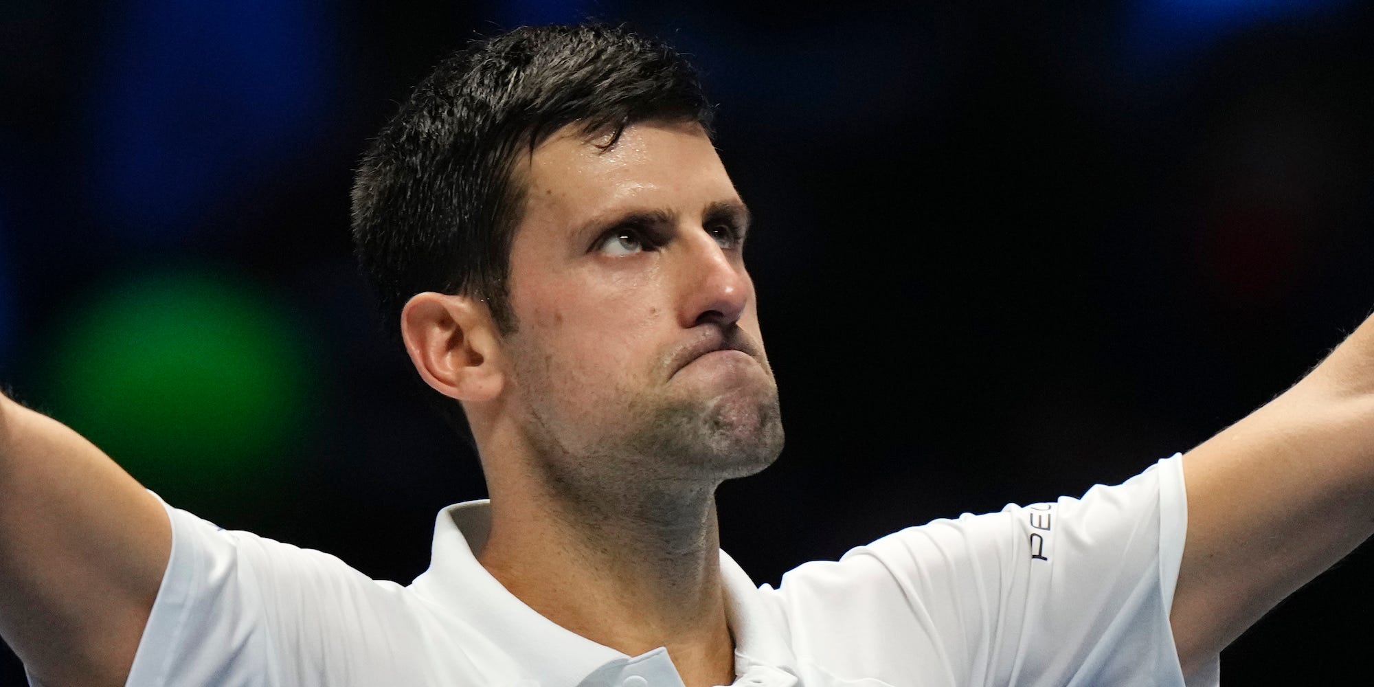 Novak Djokovic raises his arms and looks at the crowd after a match in 2021.
