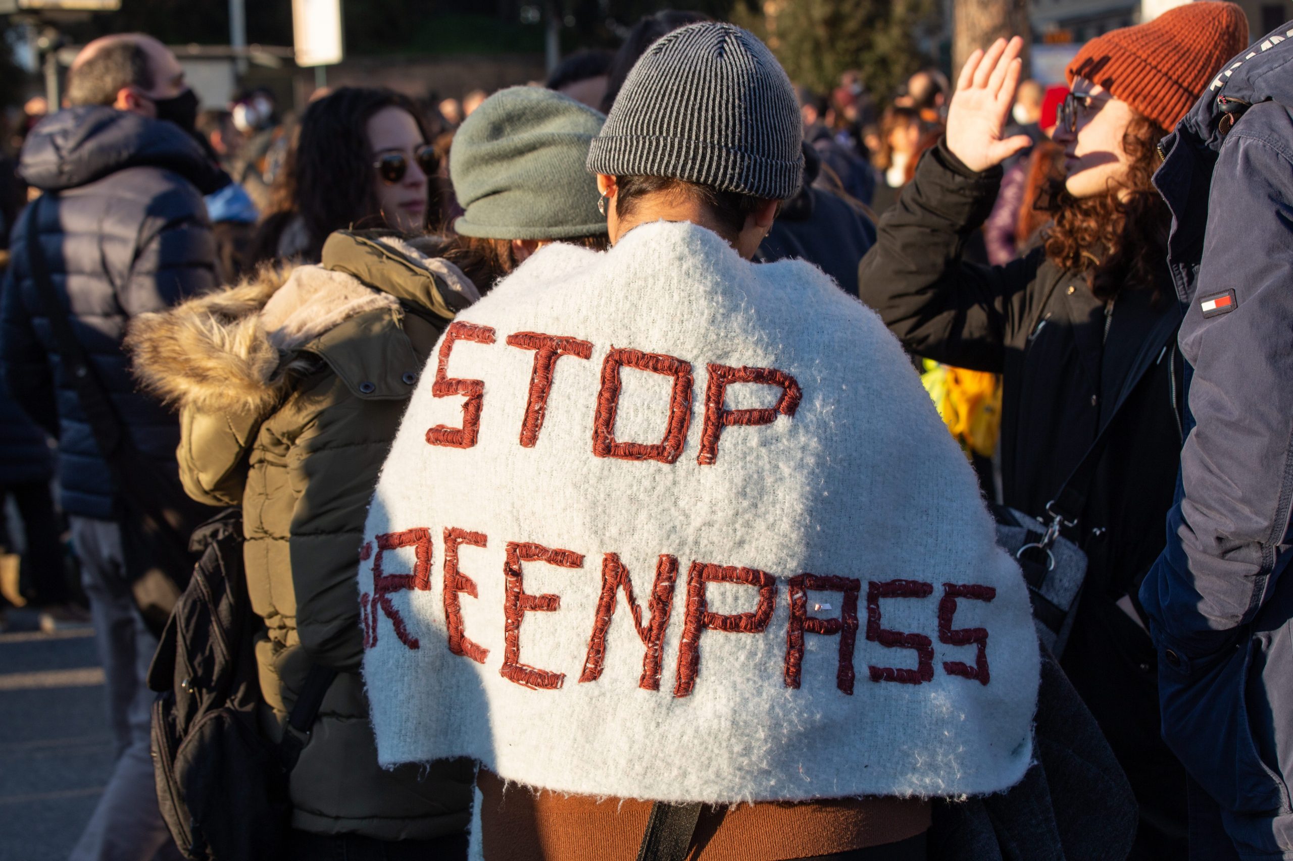 A man displays a "stop greenpass" slogan on teh back of his jacket