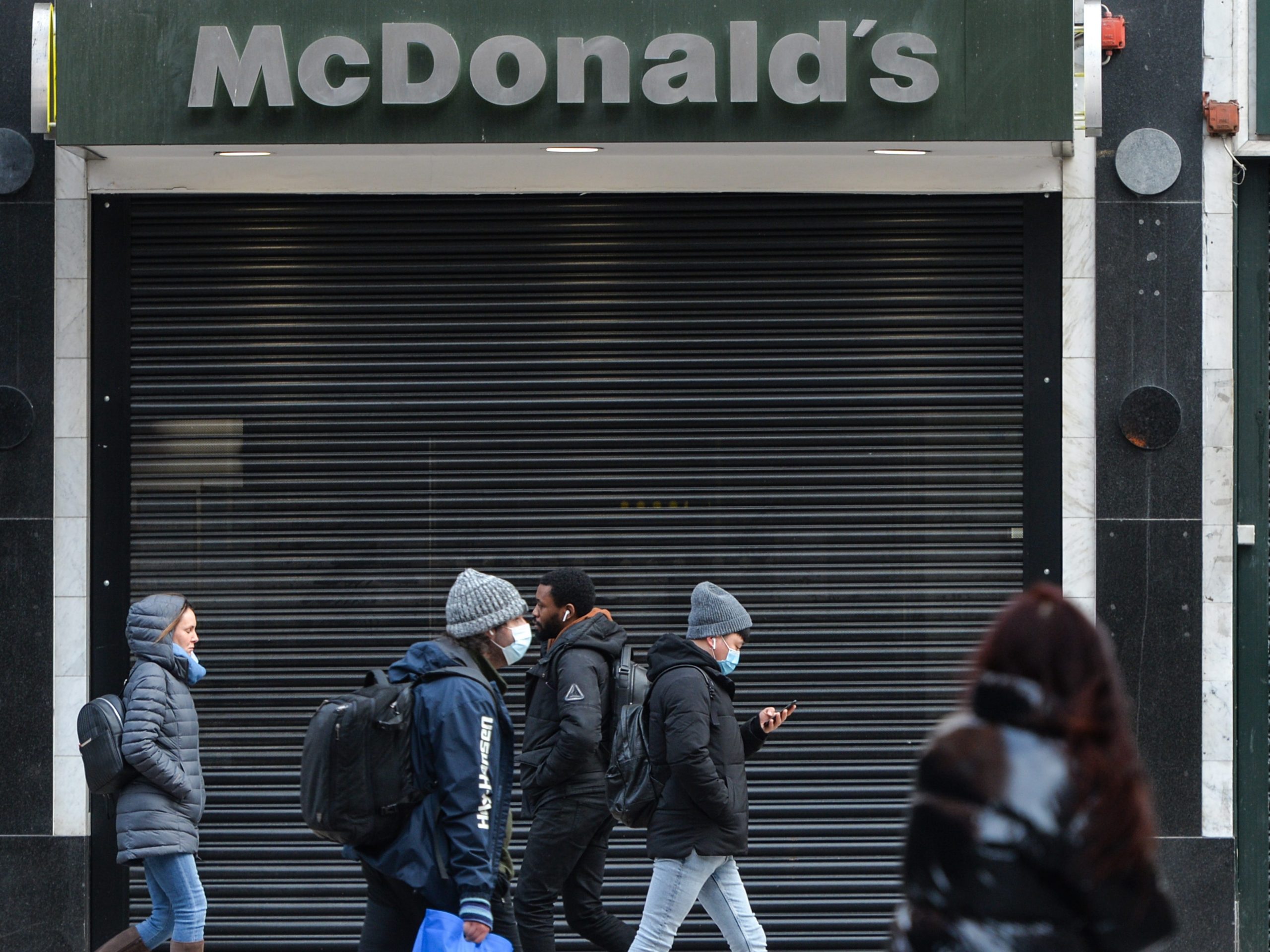 People wearing face masks walk by a closed McDonald's on Grafton Street in Dublin city center, during the COVID-19 pandemic lockdown.