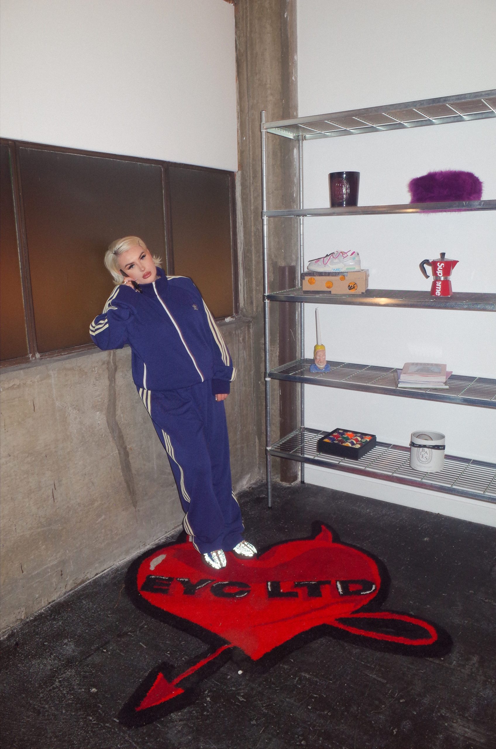 A woman in a blue tracksuit stands smiling to the camera