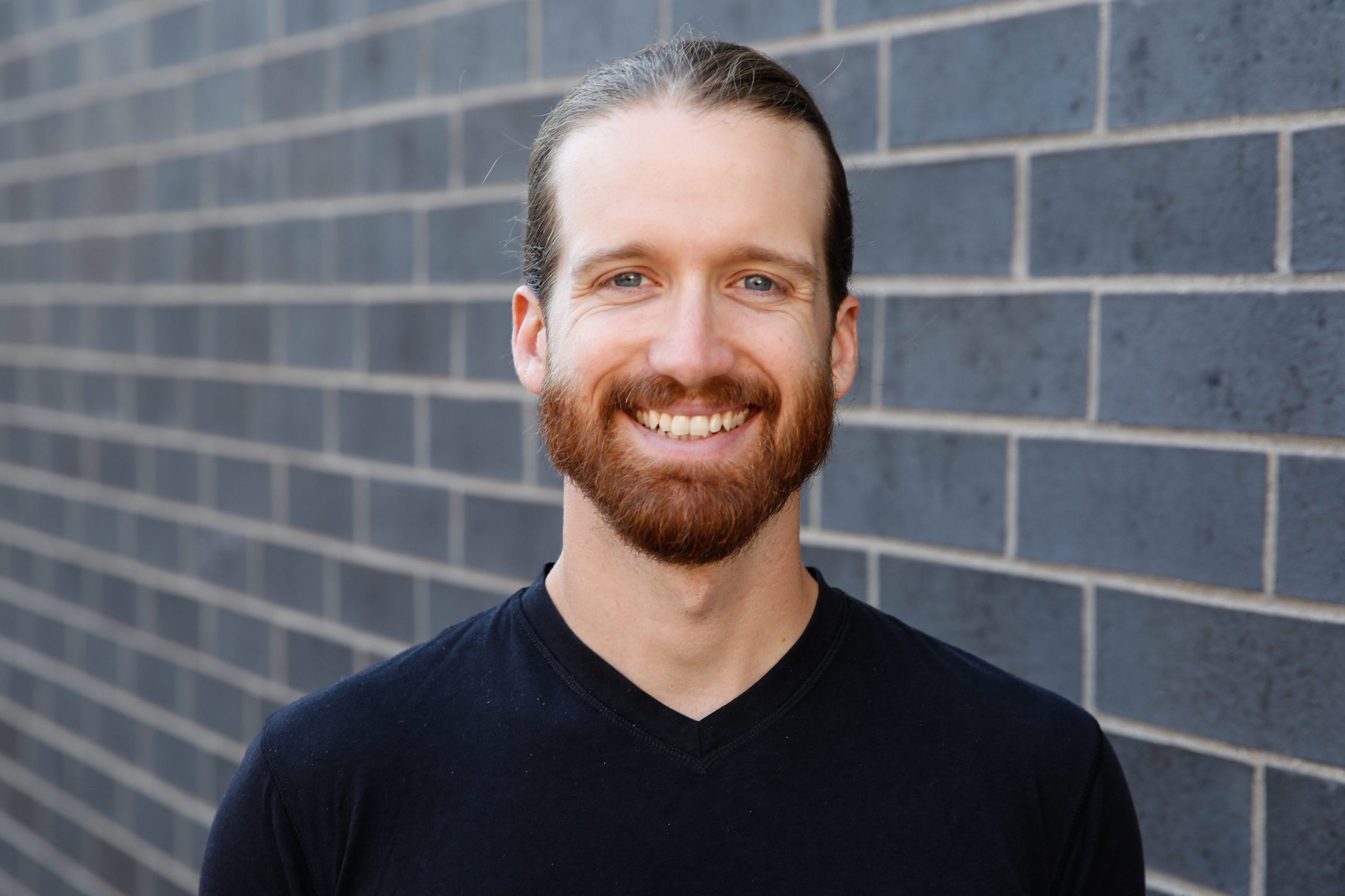 Thad Cummings' headshot, where he's standing in front of a gray brick wall.