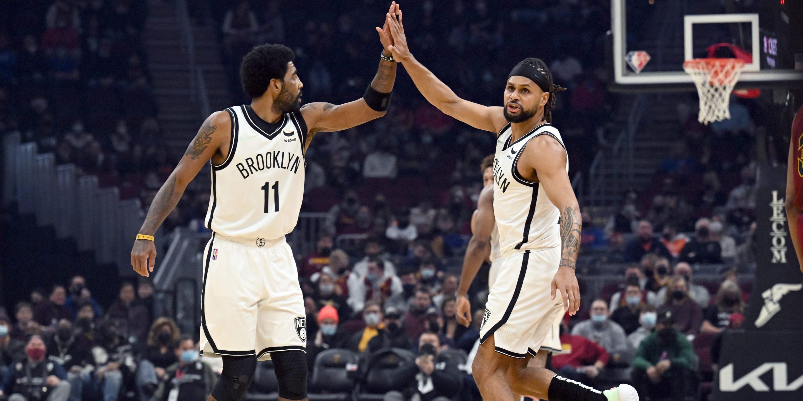 Kyrie Irving #11 and Patty Mills #8 of the Brooklyn Nets celebrate during the first quarter against the Cleveland Cavaliers at Rocket Mortgage Fieldhouse on January 17, 2022 in Cleveland, Ohio.