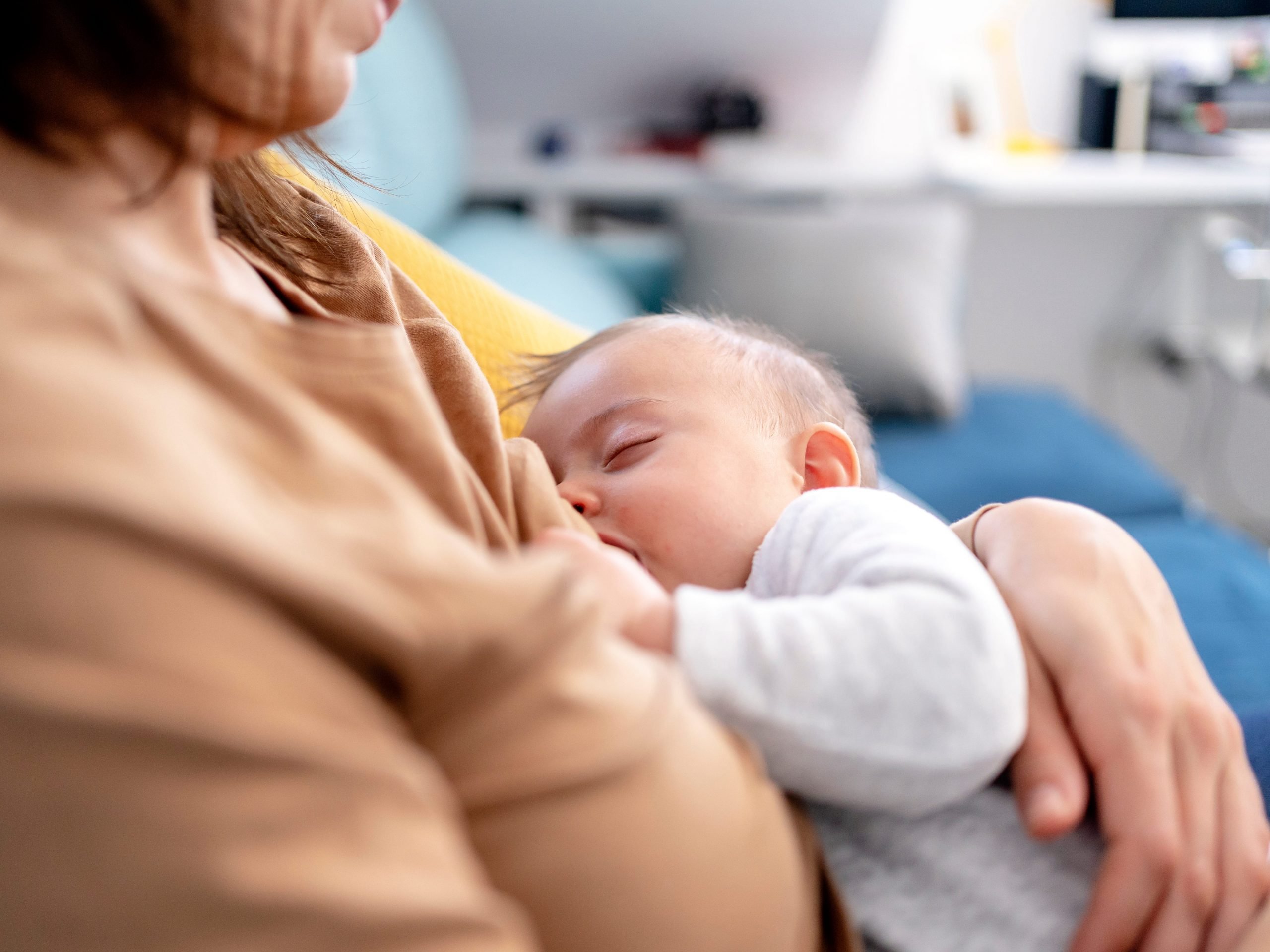 Mother breastfeeding her son at home