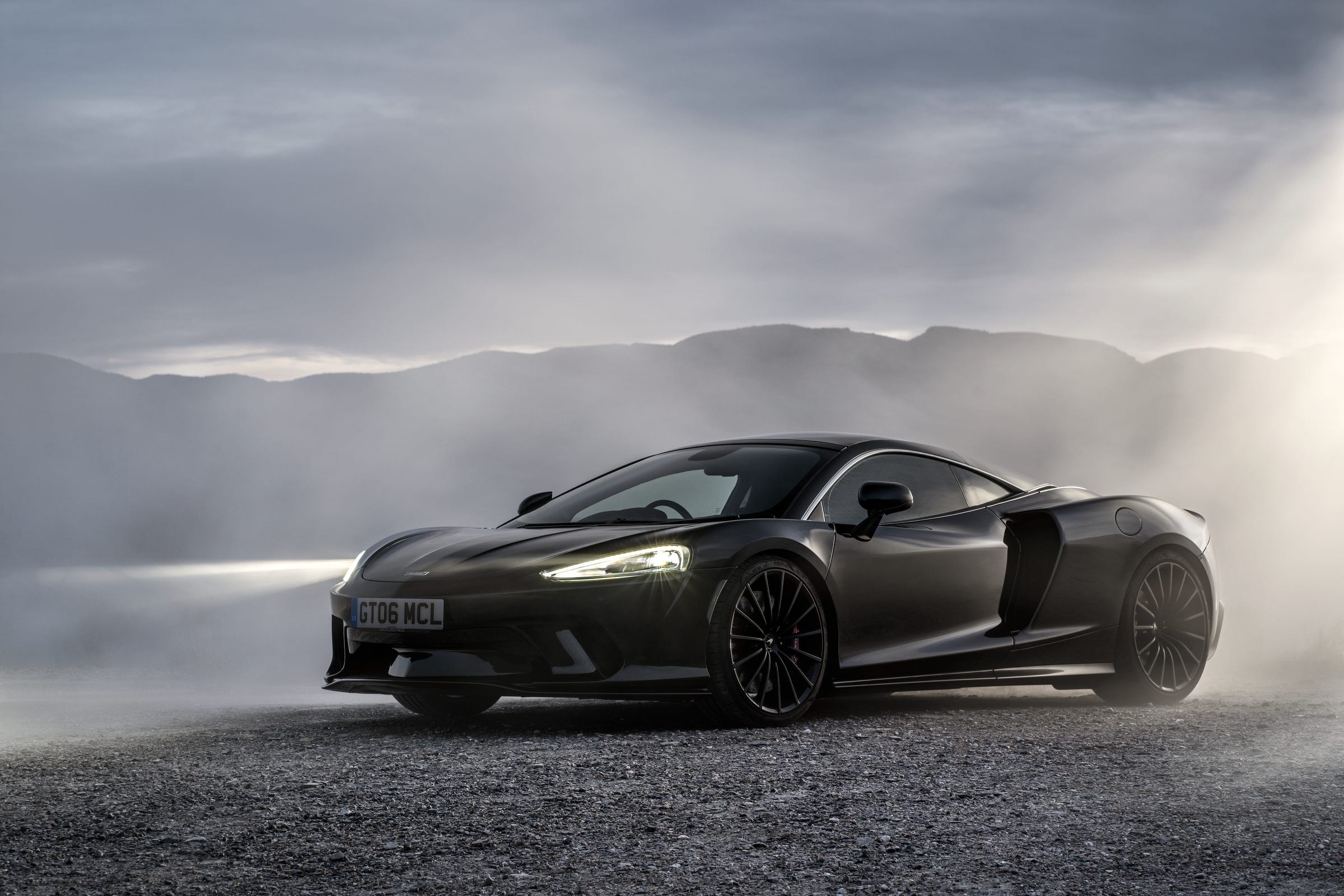 A black McLaren GT in a cloud of smoke.