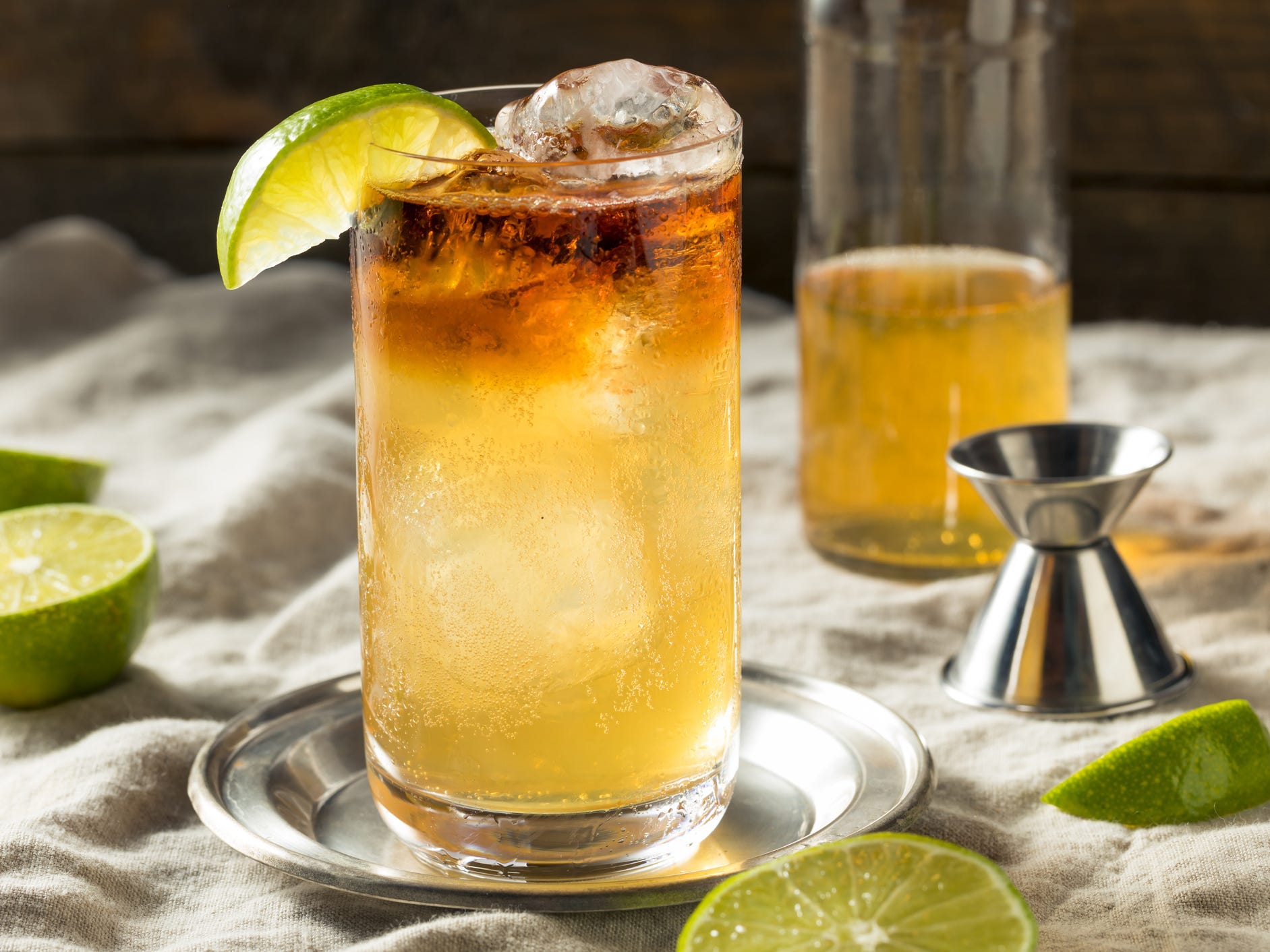 A dark and stormy cocktail garnished with a lime wedge