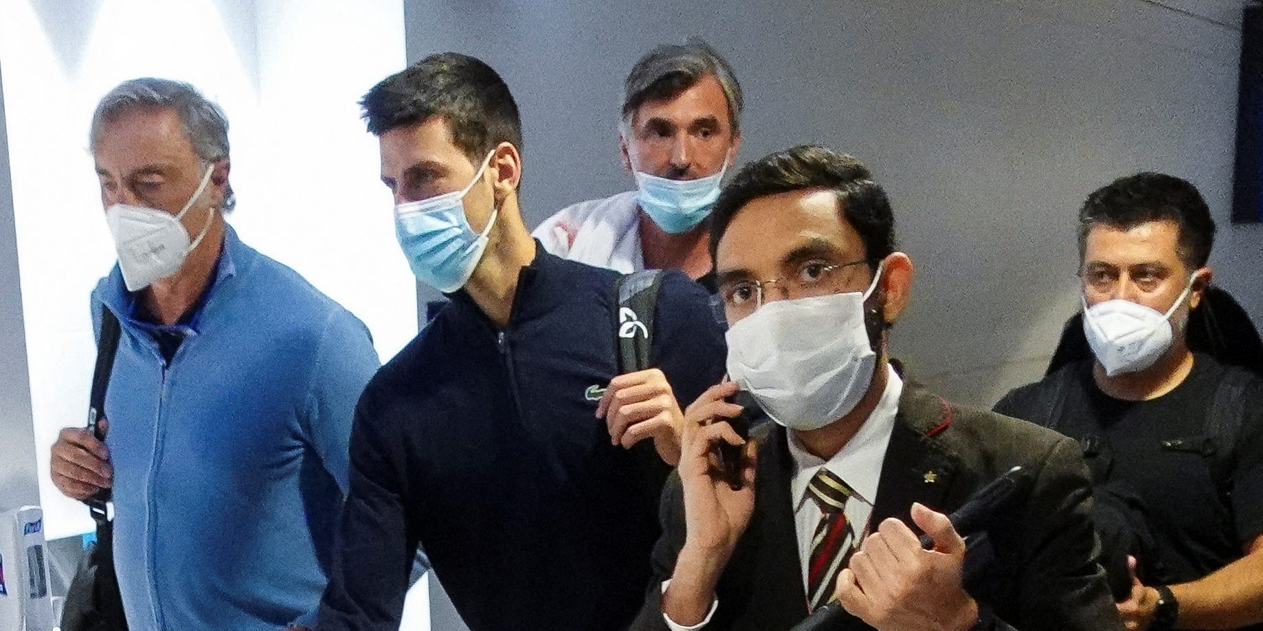 Novak Djokovic walks through Dubai Airport surrounded by his team