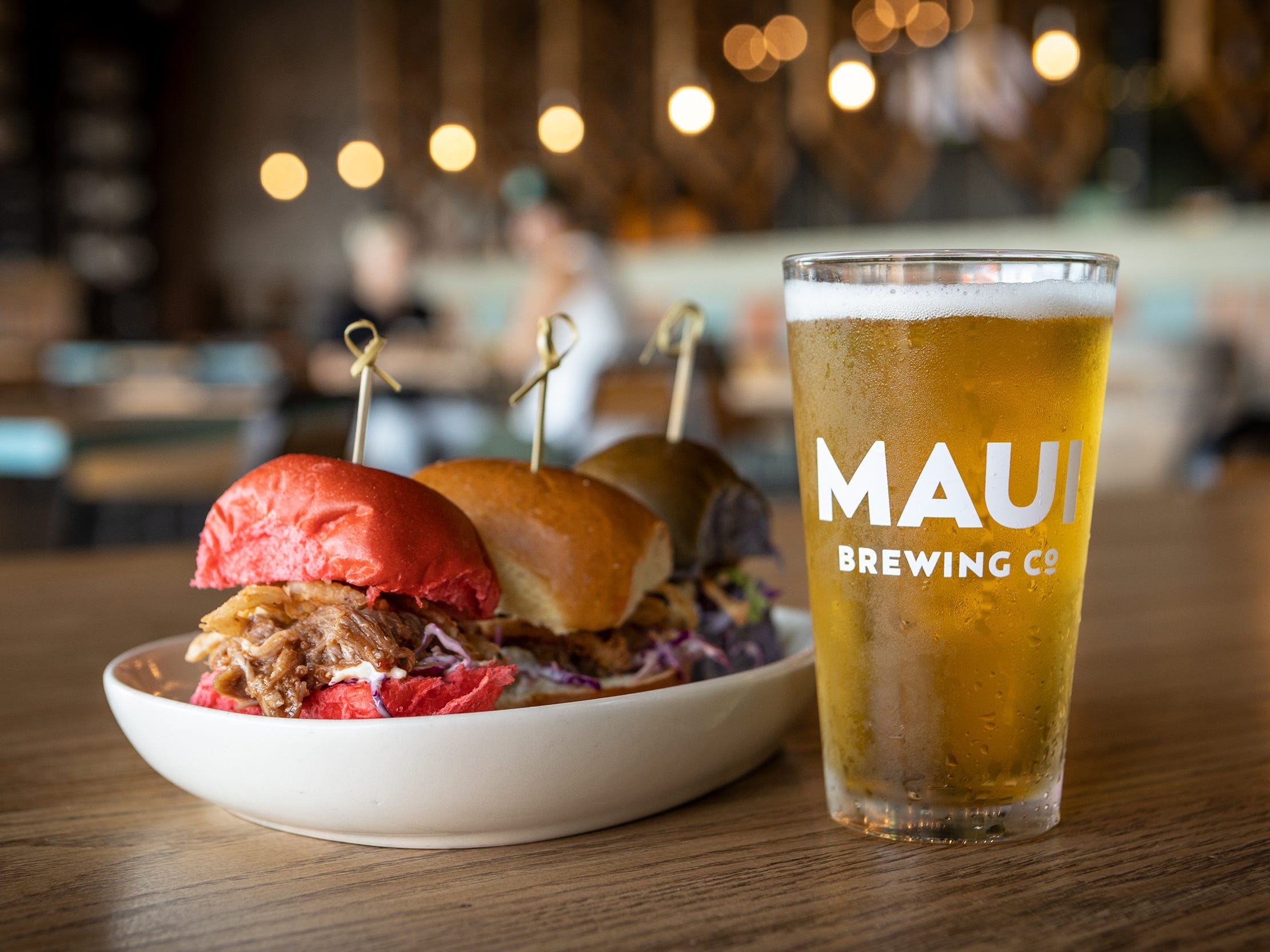 A sandwich dish and a glass of beer on a table.