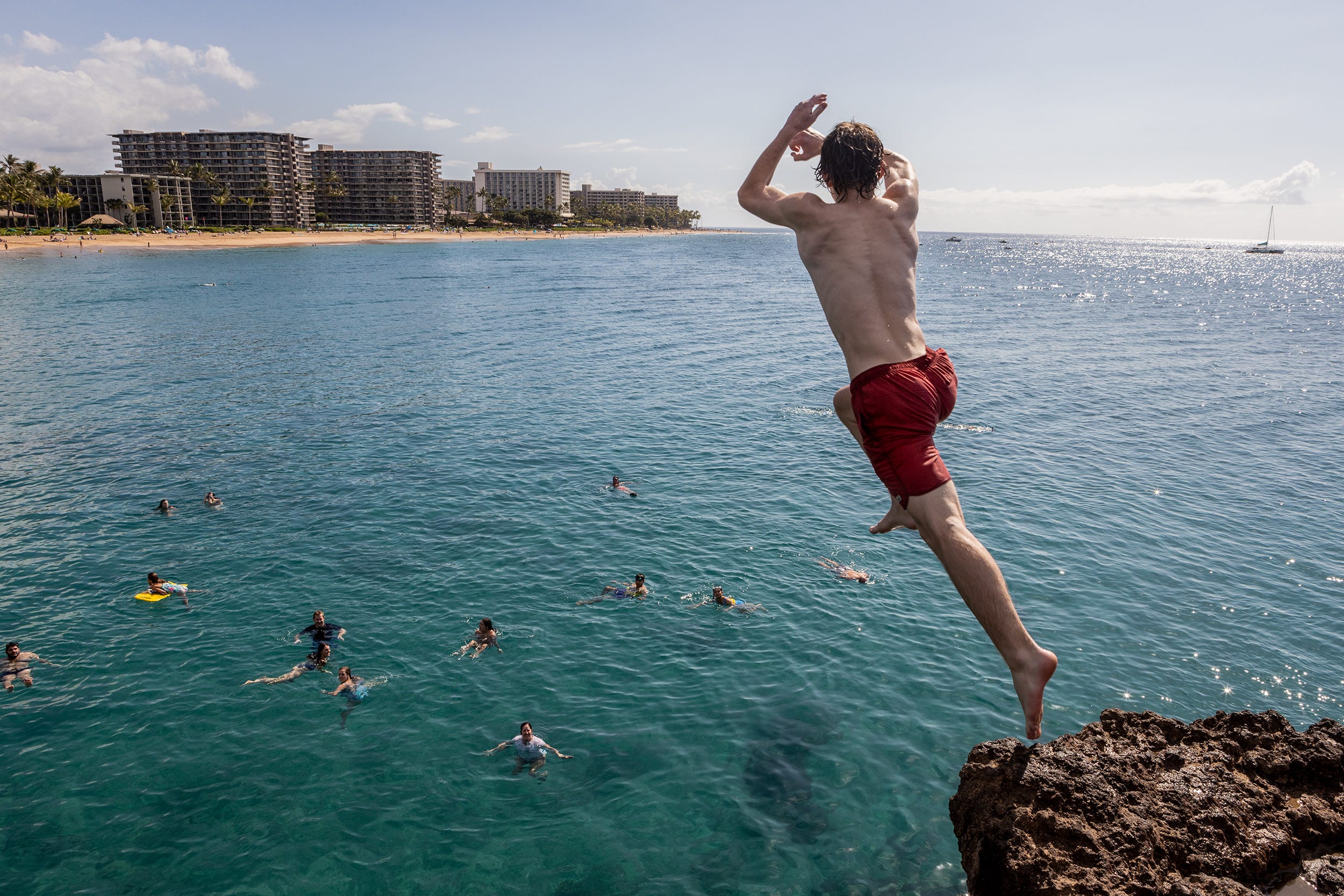A man jumping off a rock into the ocean.